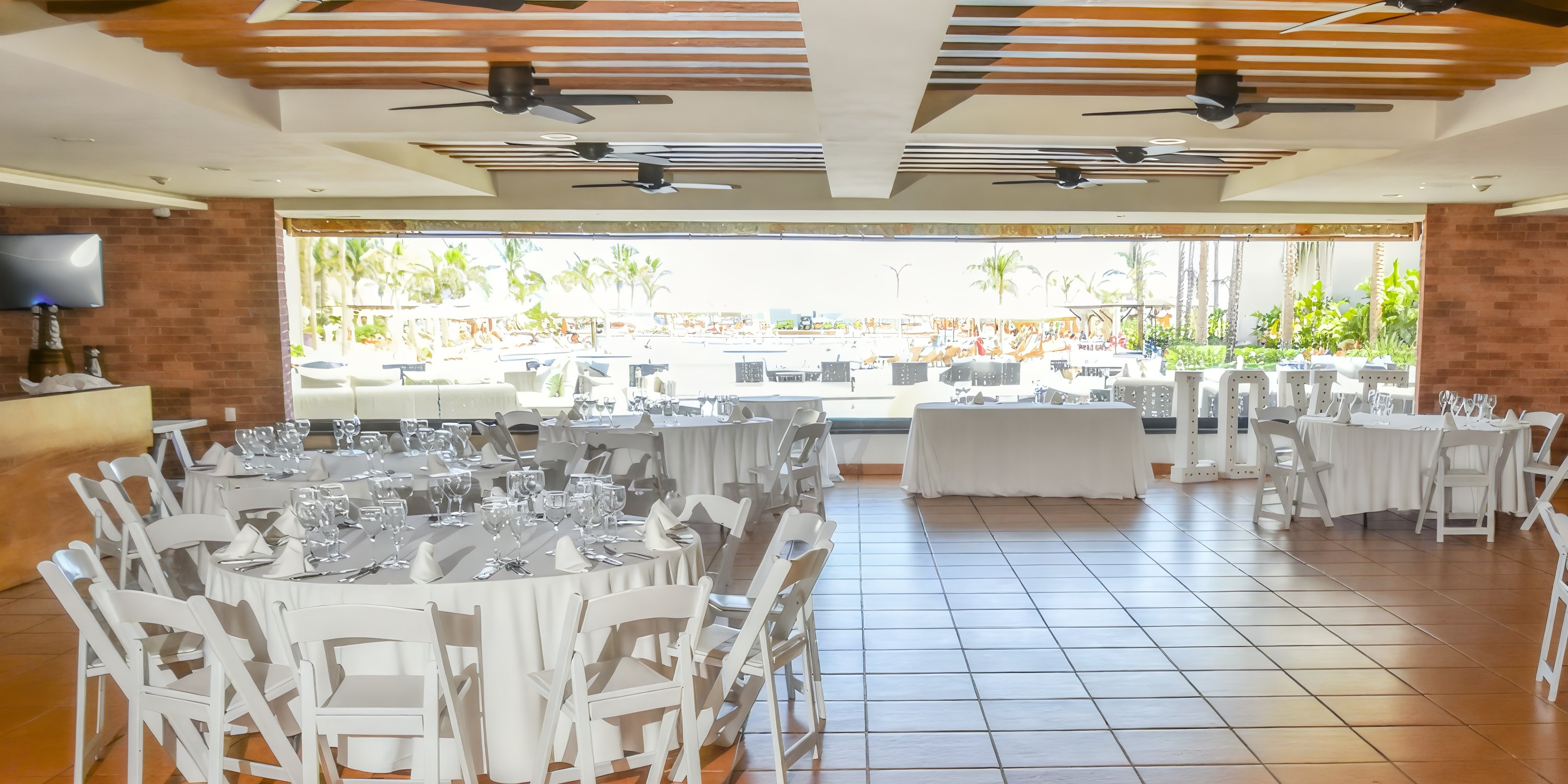Hyatt Ziva Los Cabos banquet hall with round tables, perfect for a destination wedding, overlooks pool.