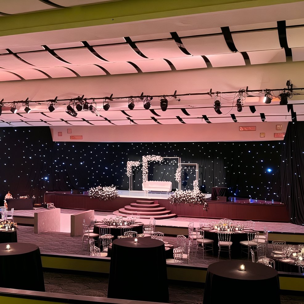 Hyatt Ziva Los Cabos wedding hall with decorated stage, round tables, and sparkling star-like lights.