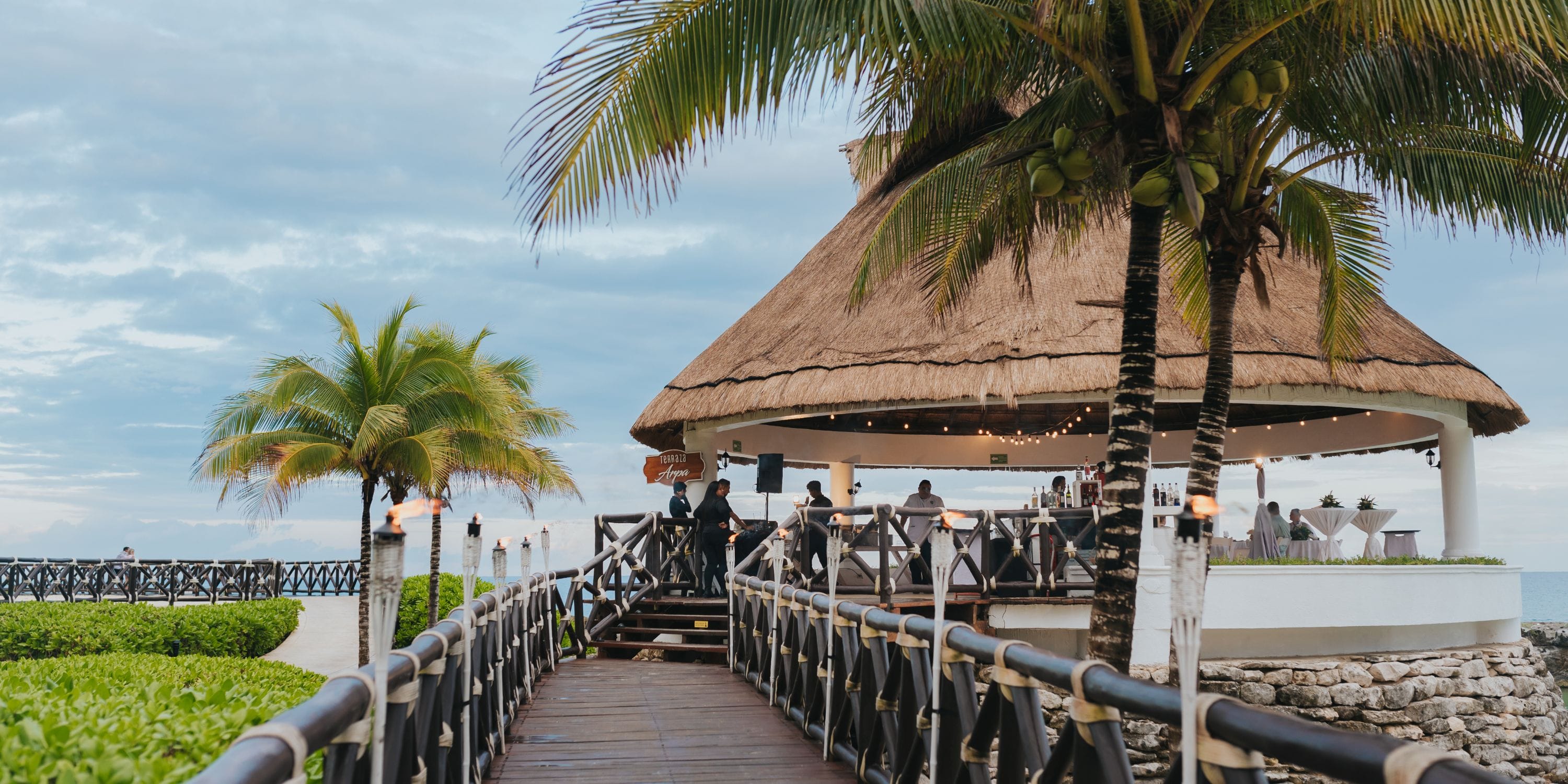 Thatched-roof pavilion at Hard Rock Riviera Maya, perfect for a destination wedding, with sunset ocean views and palm trees.
