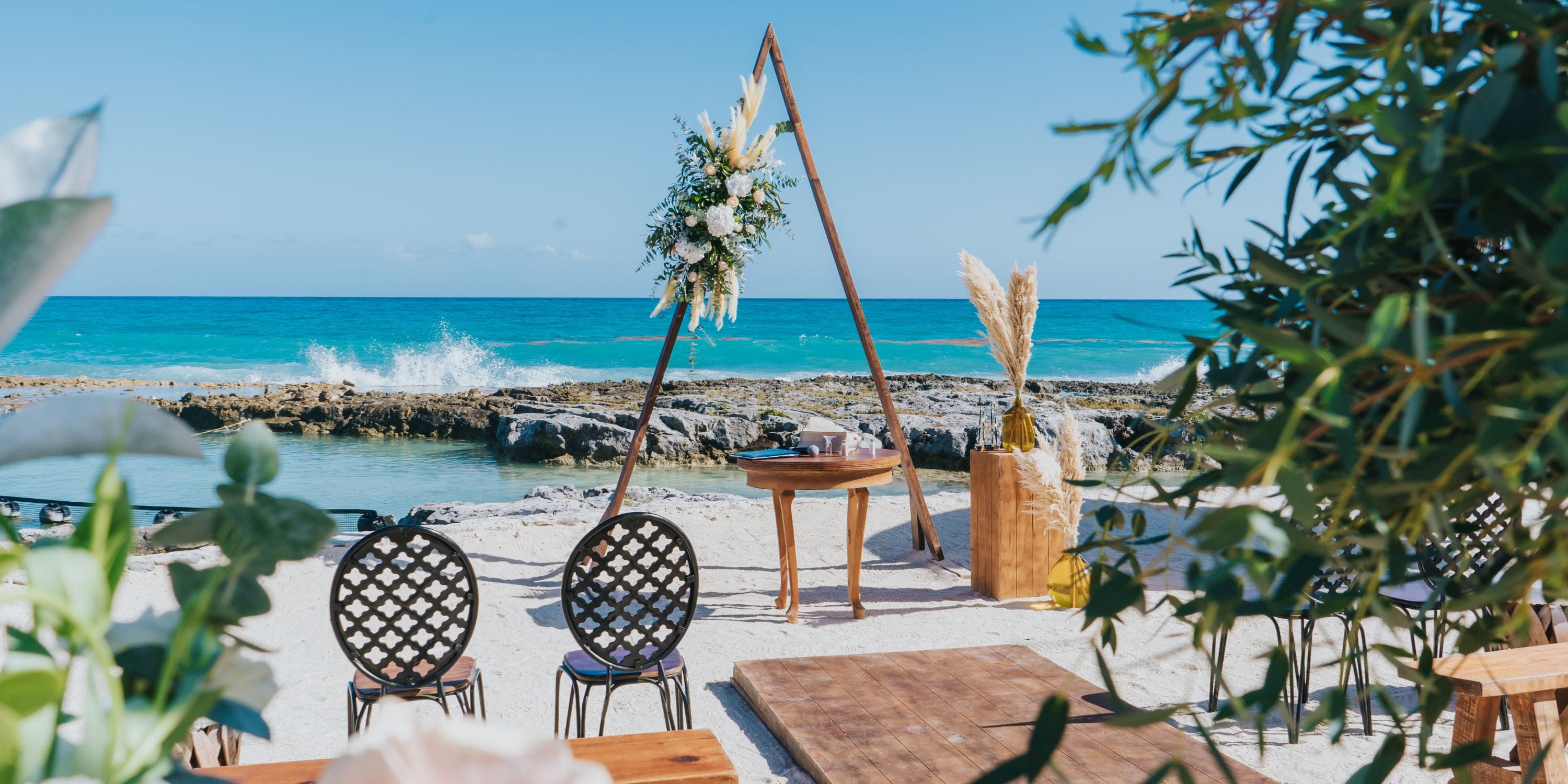 Destination wedding setup on the beach at Hard Rock Riviera Maya, featuring an arch and floral displays.