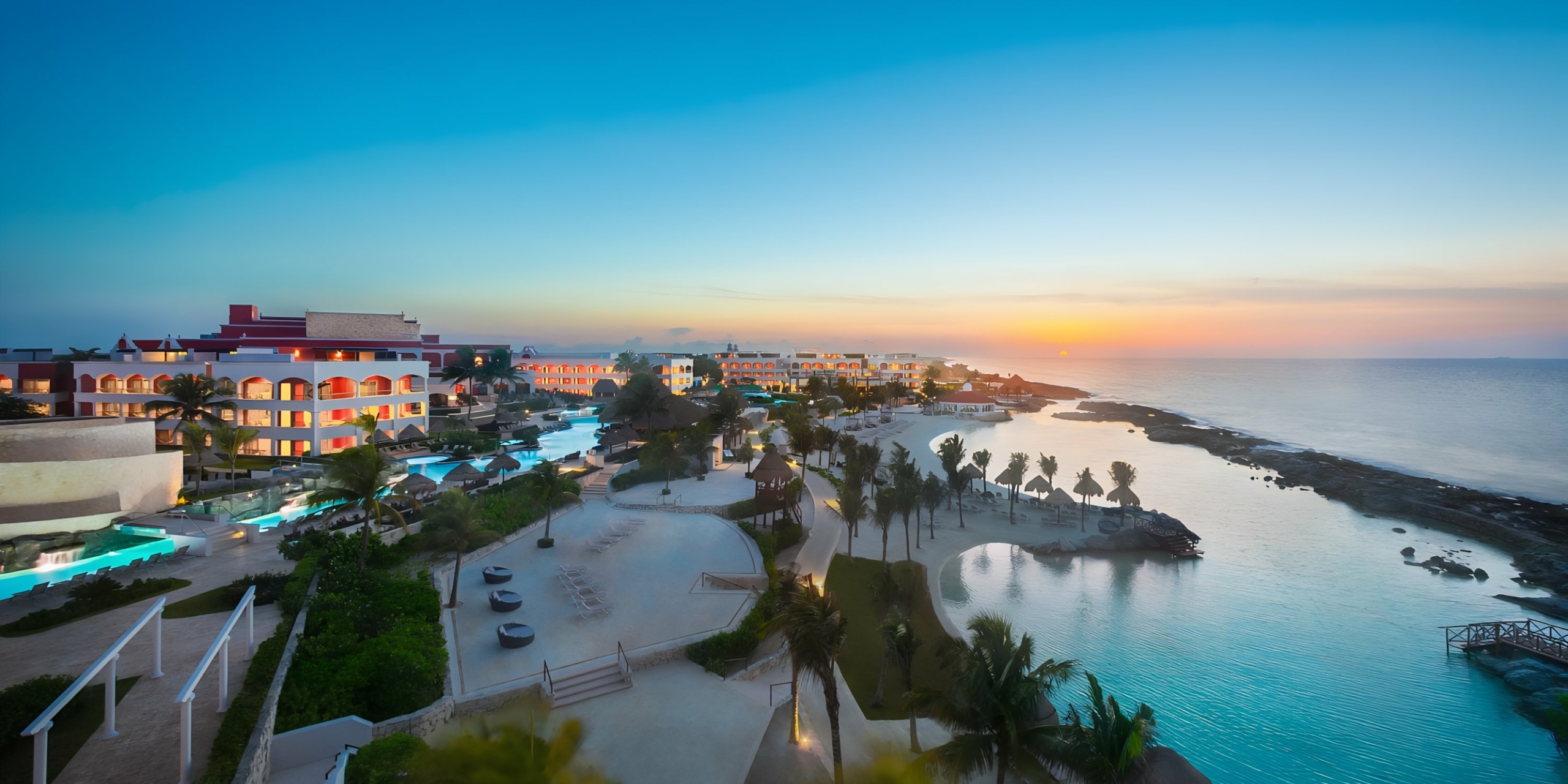 Coastal Hard Rock Riviera Maya wedding resort at sunset with palm trees and beachfront accommodations.