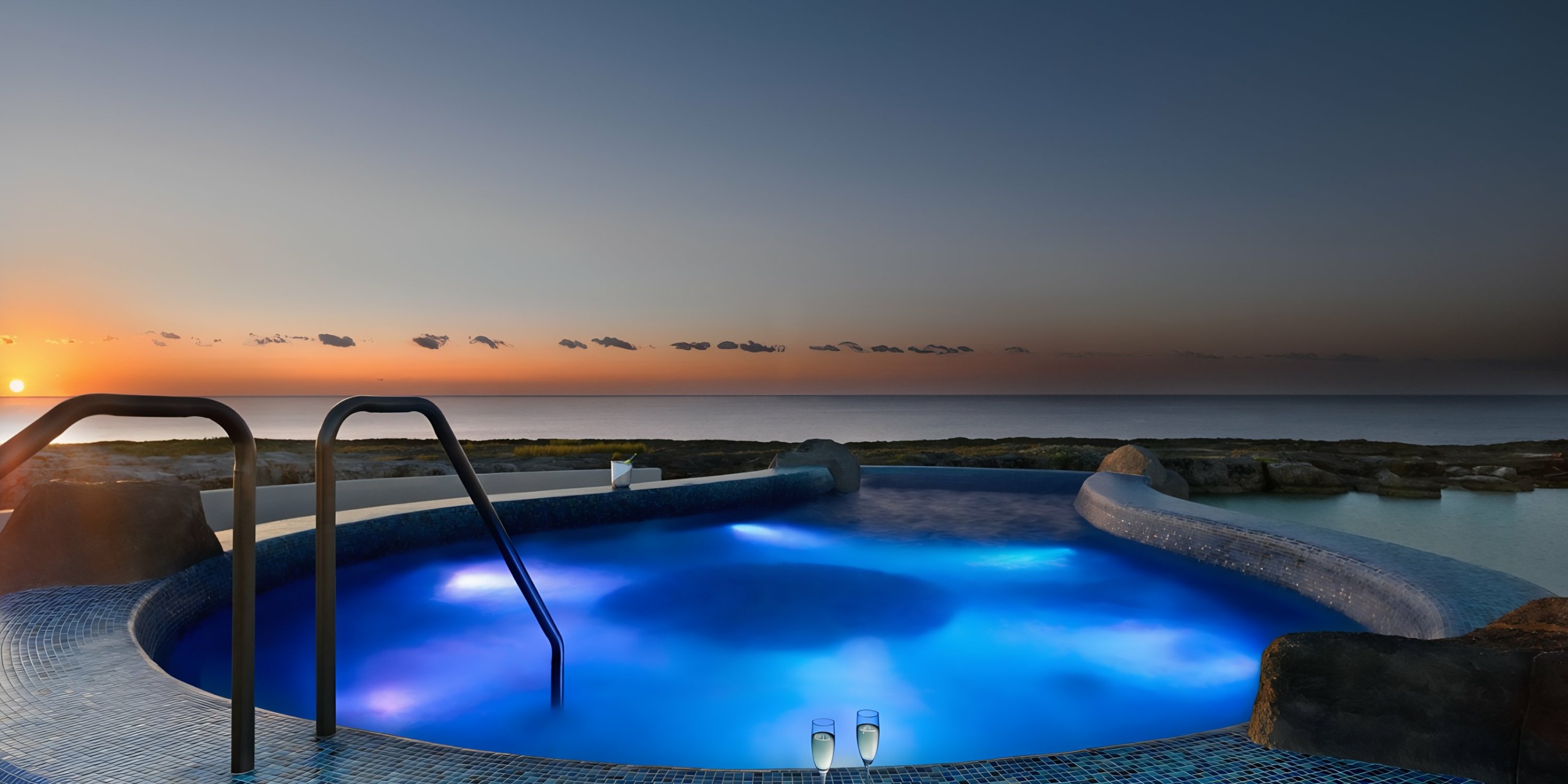 Illuminated pool overlooking the ocean at sunset at the Hard Rock Riviera Maya wedding resort.