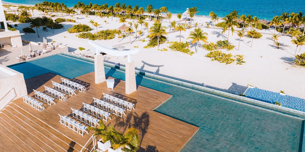 Destination wedding on the deck by the infinity pool at Majestic Elegance Costa Mujeres, overlooking the ocean.
