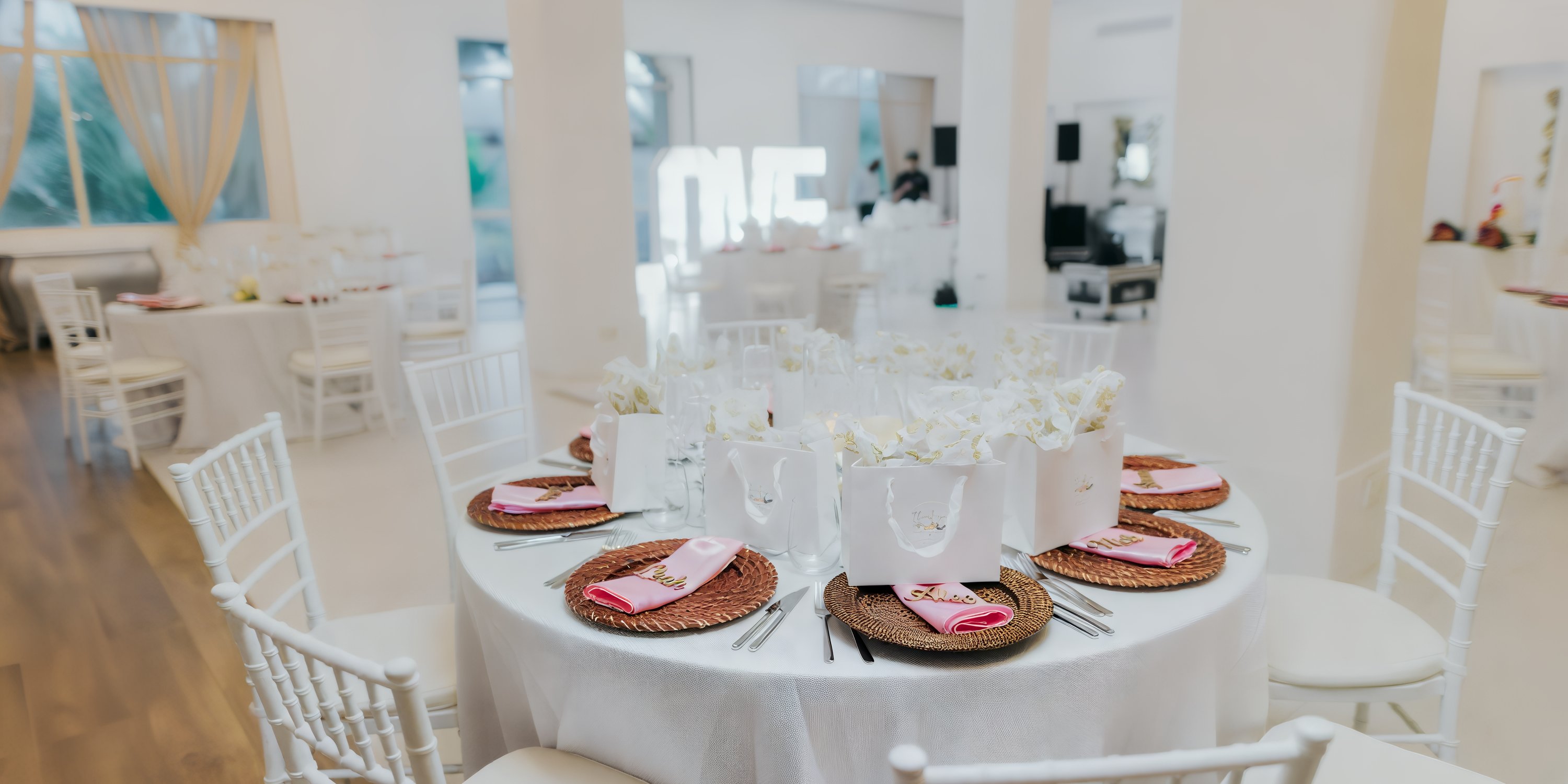 Destination wedding table at Majestic Elegance Punta Cana with white decor, gift bags, and pink napkins.