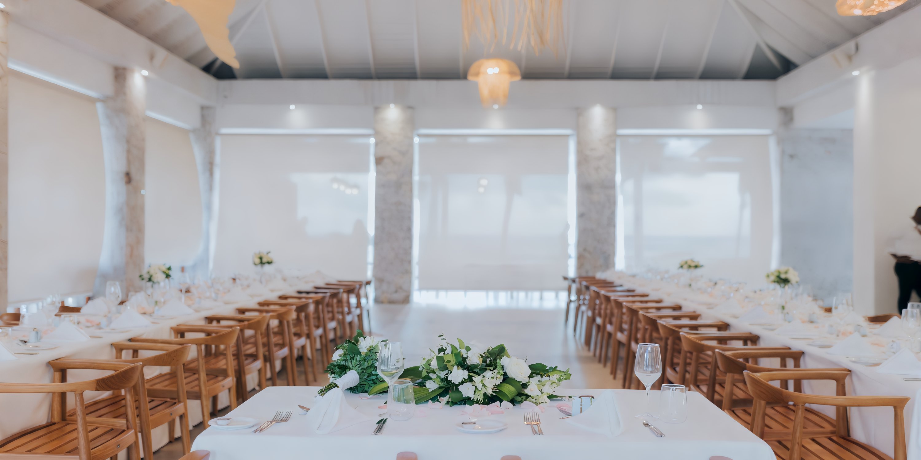 Majestic Elegance Punta Cana destination wedding: long banquet table, white linens, floral centerpiece, wood chairs.