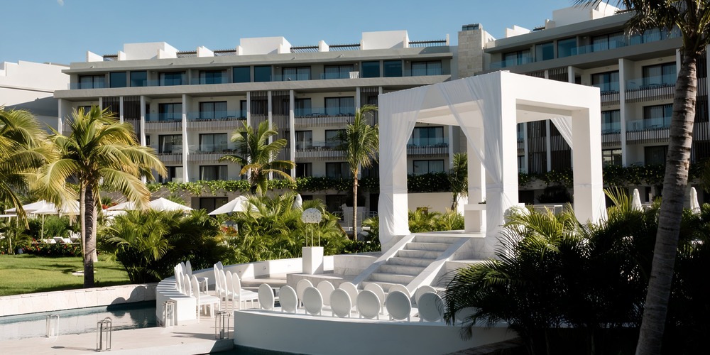 A stunning canopy labeled Majestic Elegance, complete with seating, offers a perfect setting for a destination wedding as it faces a modern building.