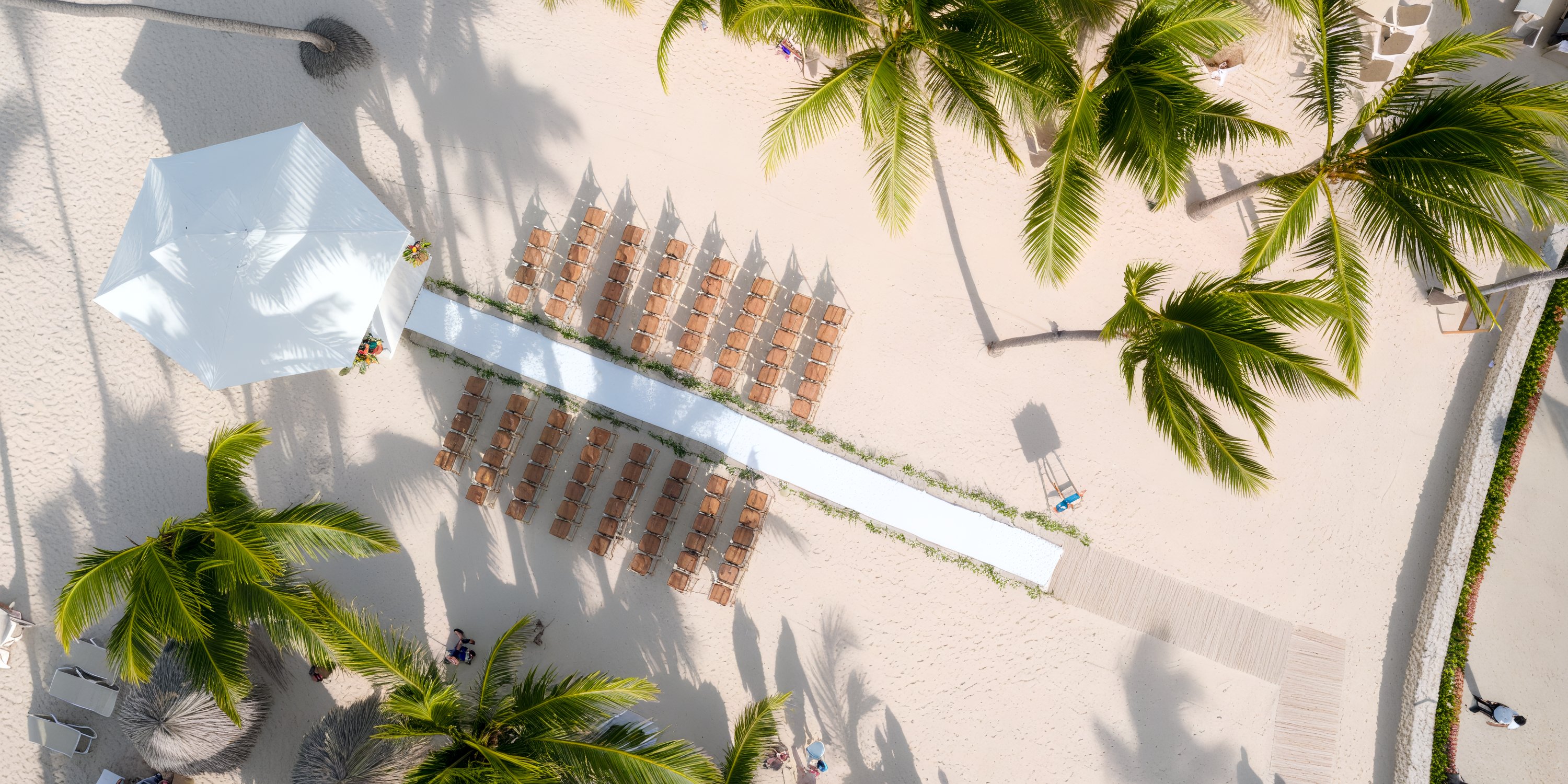 Aerial view of a destination wedding setup at Majestic Colonial, featuring chairs and palm trees.