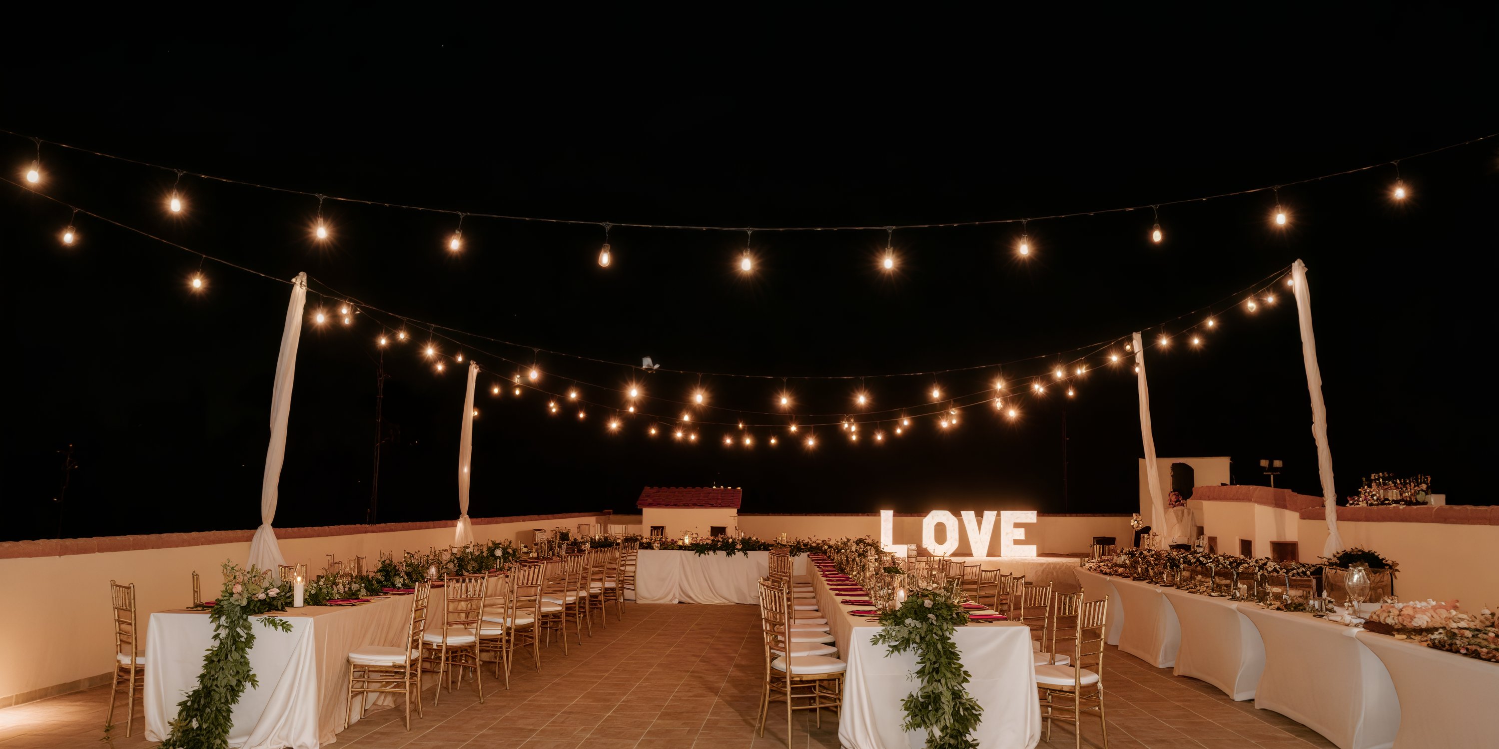 Destination wedding setup outdoors with string lights and a glowing "LOVE" sign at Majestic Colonial.