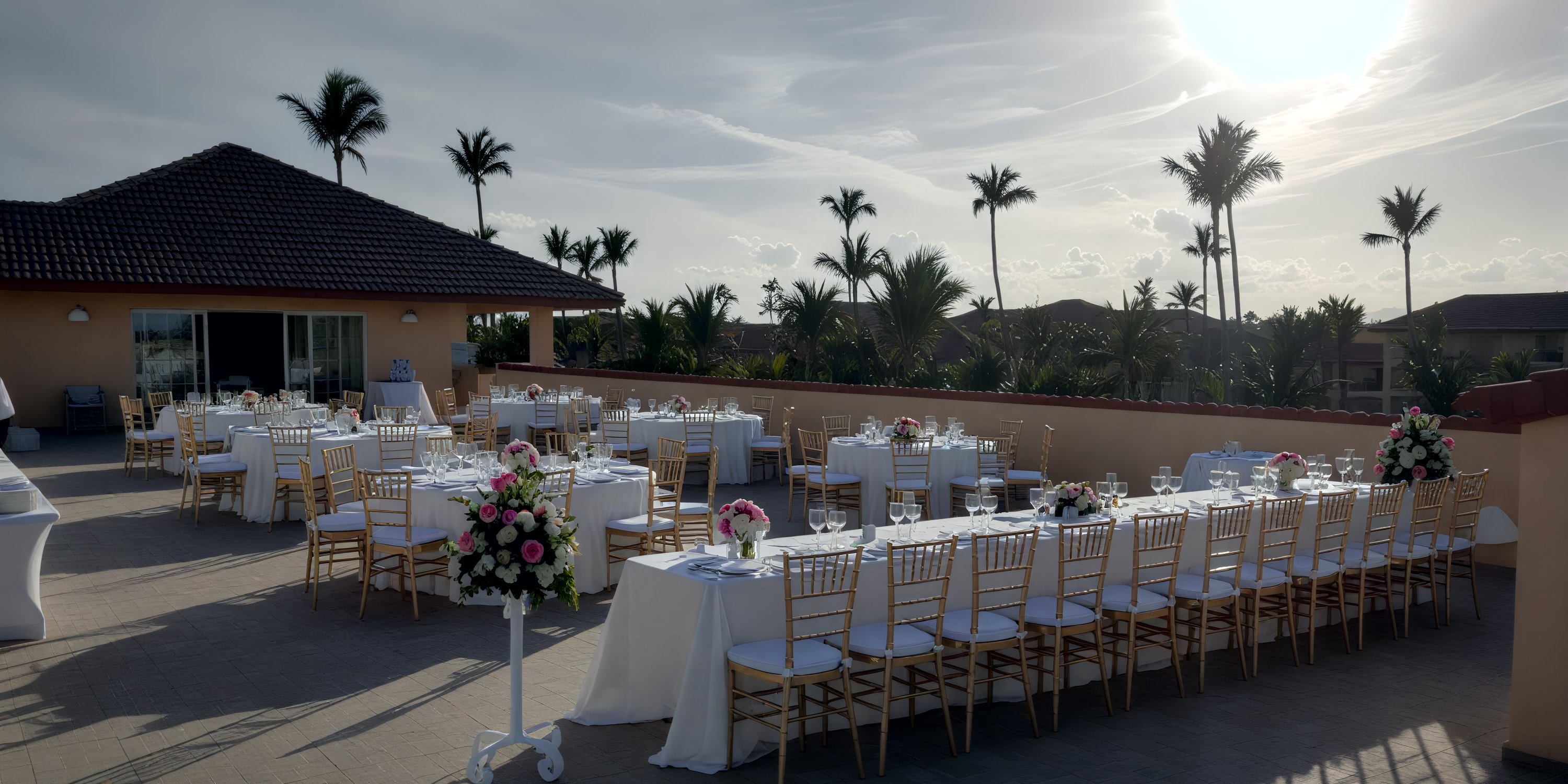 Elegant destination wedding setup with floral centerpieces and palm décor for an outdoor celebration.