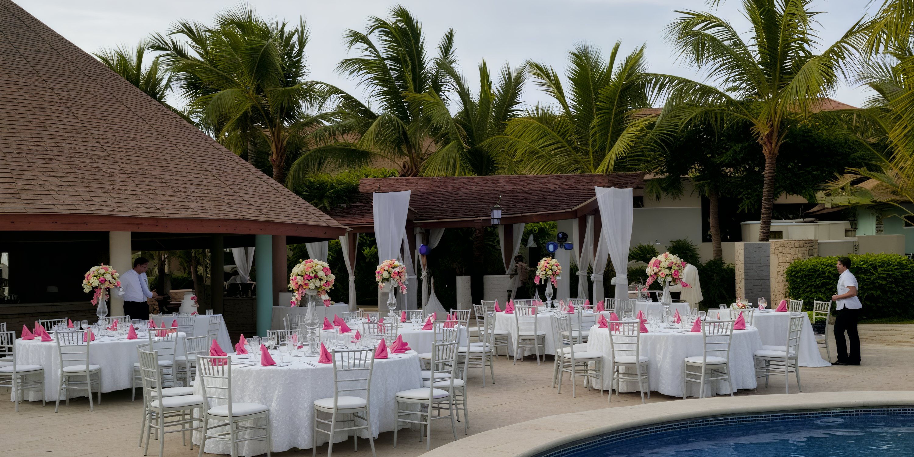 Destination wedding at Majestic Colonial: outdoor poolside scene with round tables and pink napkins.