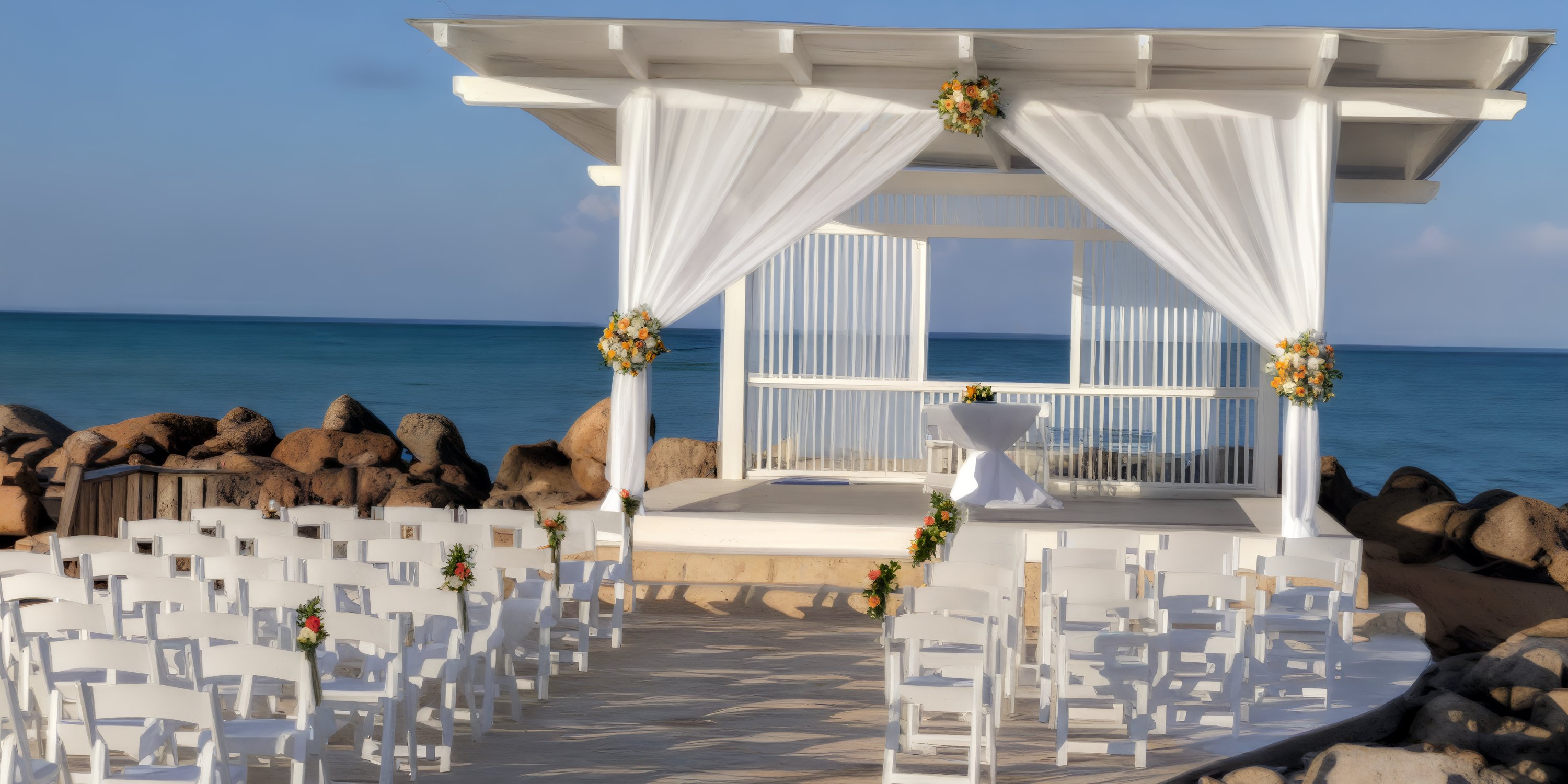 Destination wedding setup at Royalton Blue Waters with white chairs, florals, and a canopy by the beach.