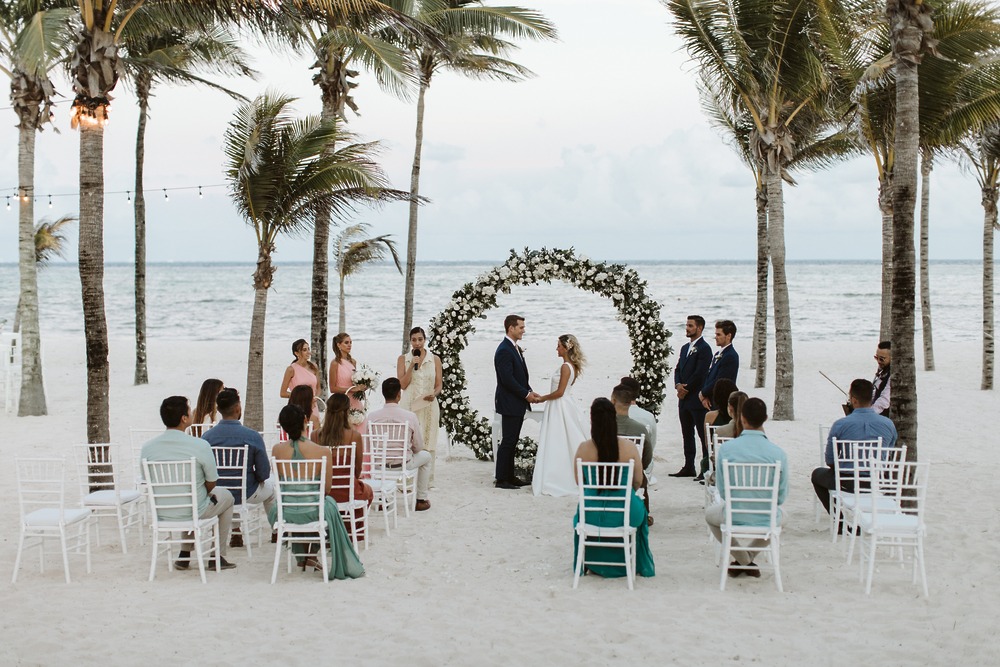 A destination wedding at Hotel RIU Ocho Rios with guests, a floral arch, and palm trees in the background.