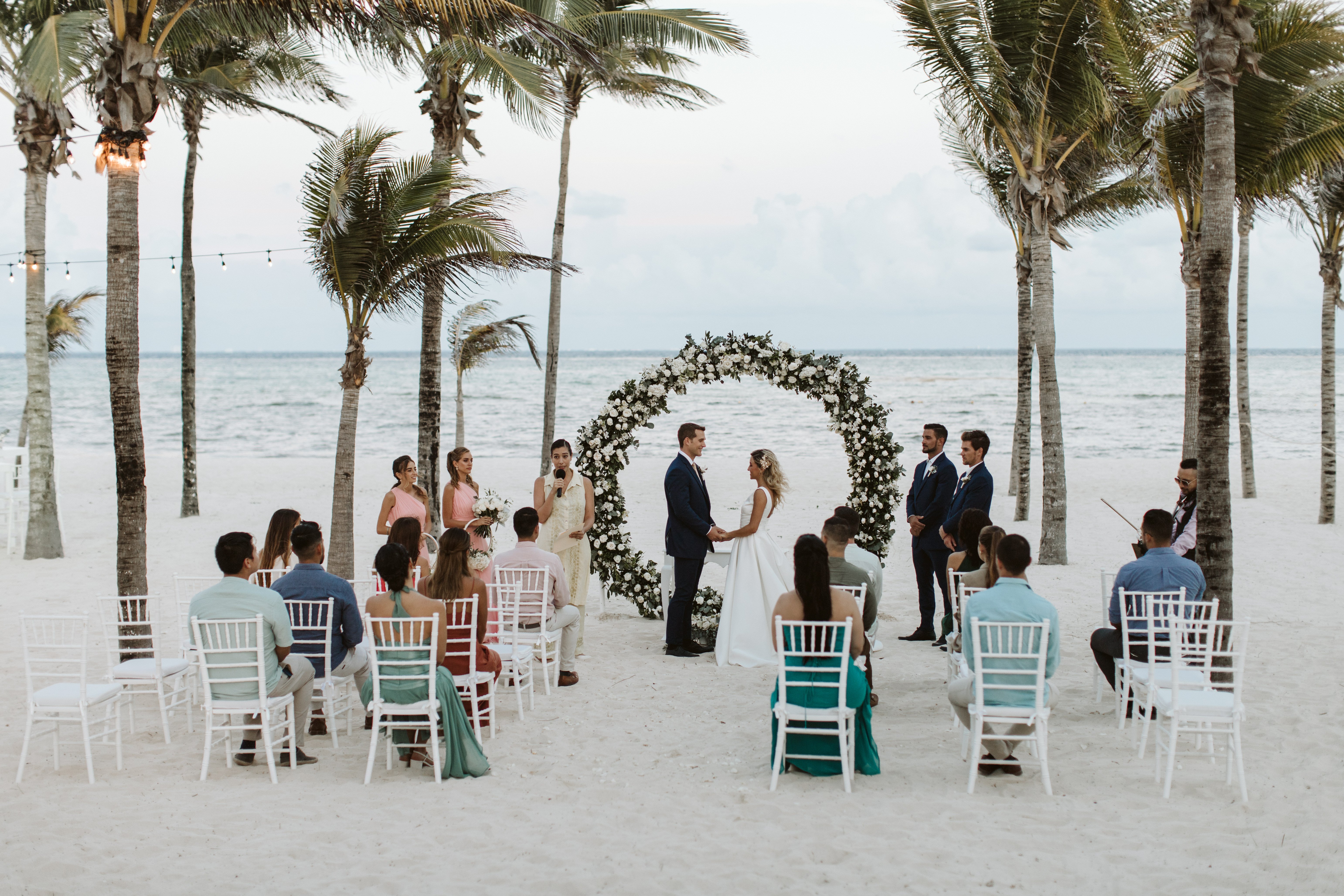 A destination wedding at Hotel RIU Ocho Rios with guests, a floral arch, and palm trees in the background.