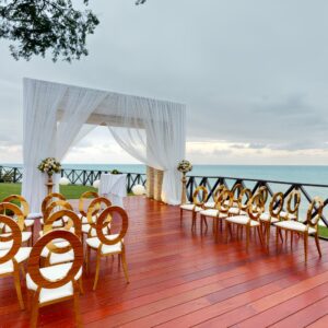 A destination wedding setup featuring wooden chairs and a beautiful arch by the sea.