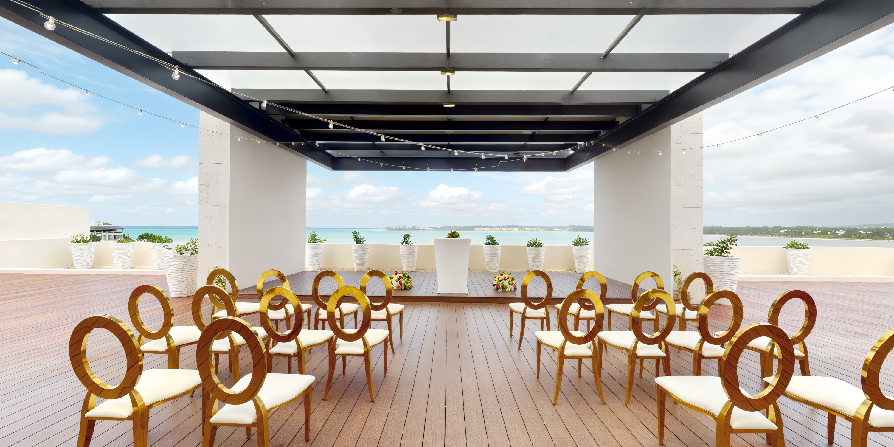 A destination wedding at Royalton Negril is beautifully arranged with wooden chairs set up under a charming seaside pergola.