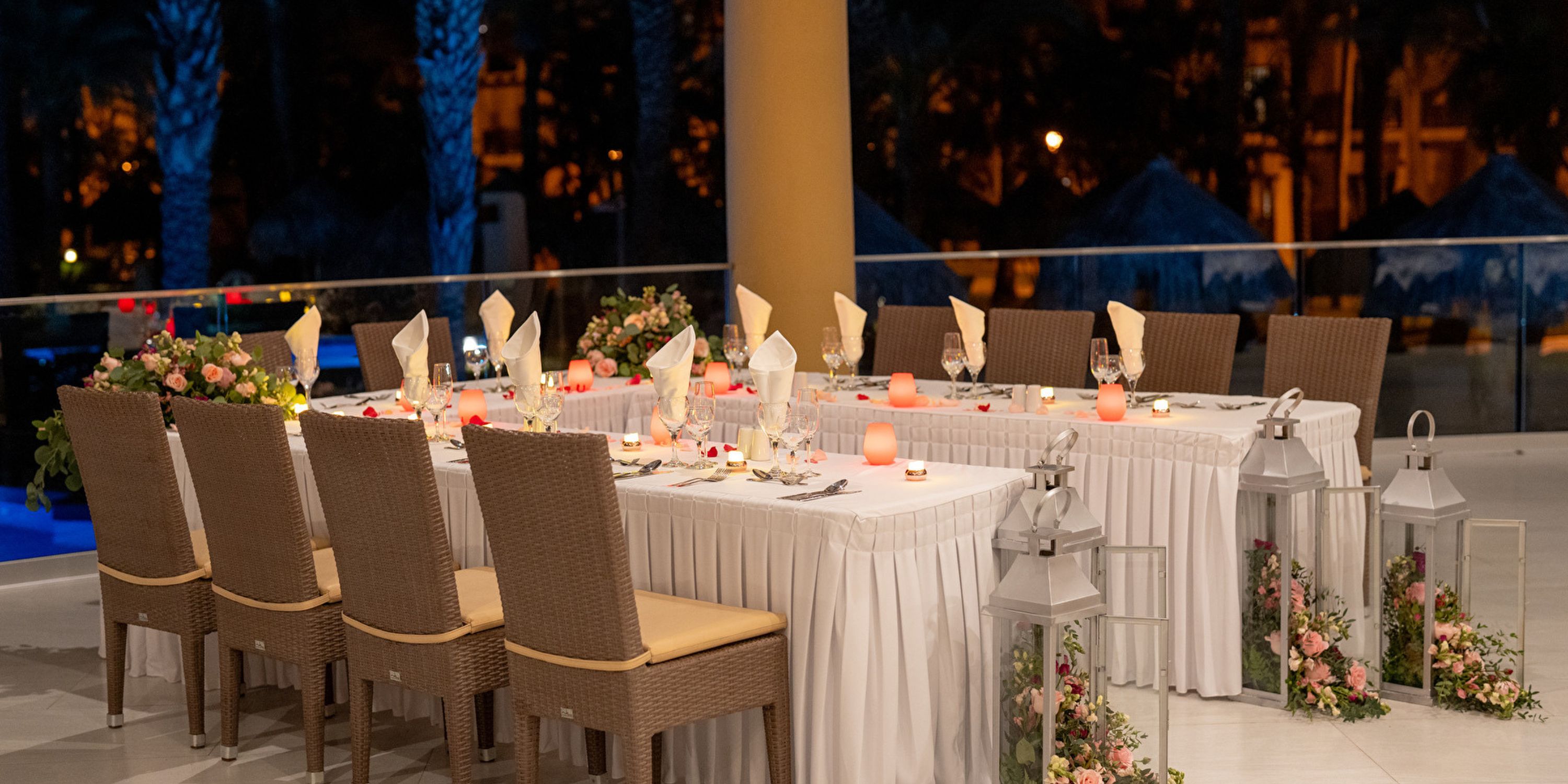 Outdoor dining at Hotel Riu Santa Fe offers woven chairs, white linens, and floral d&eacute;cor for a wedding.