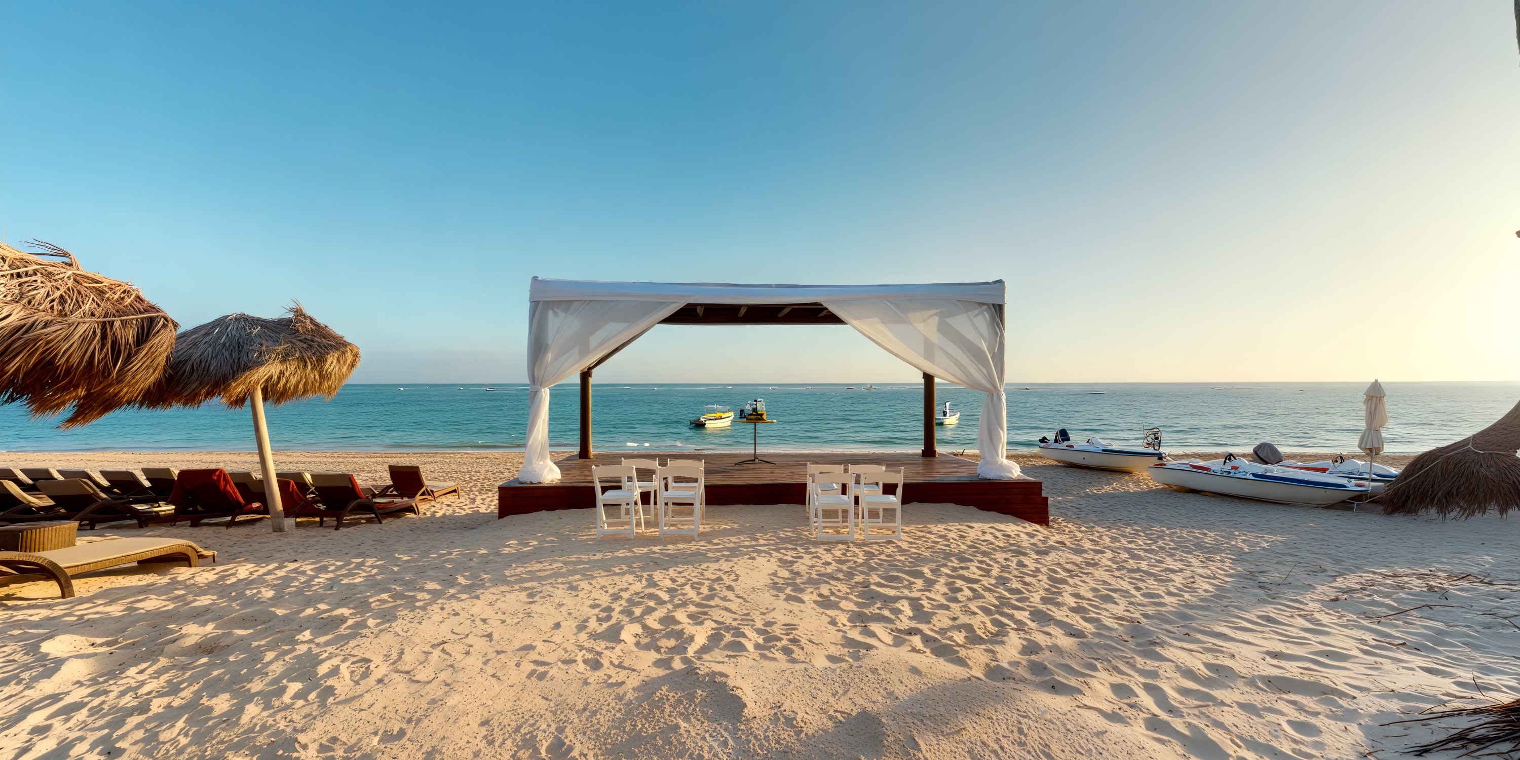 Royalton Bavaro destination wedding setup: white canopy, chairs on sand, ocean view, boats, clear sky.