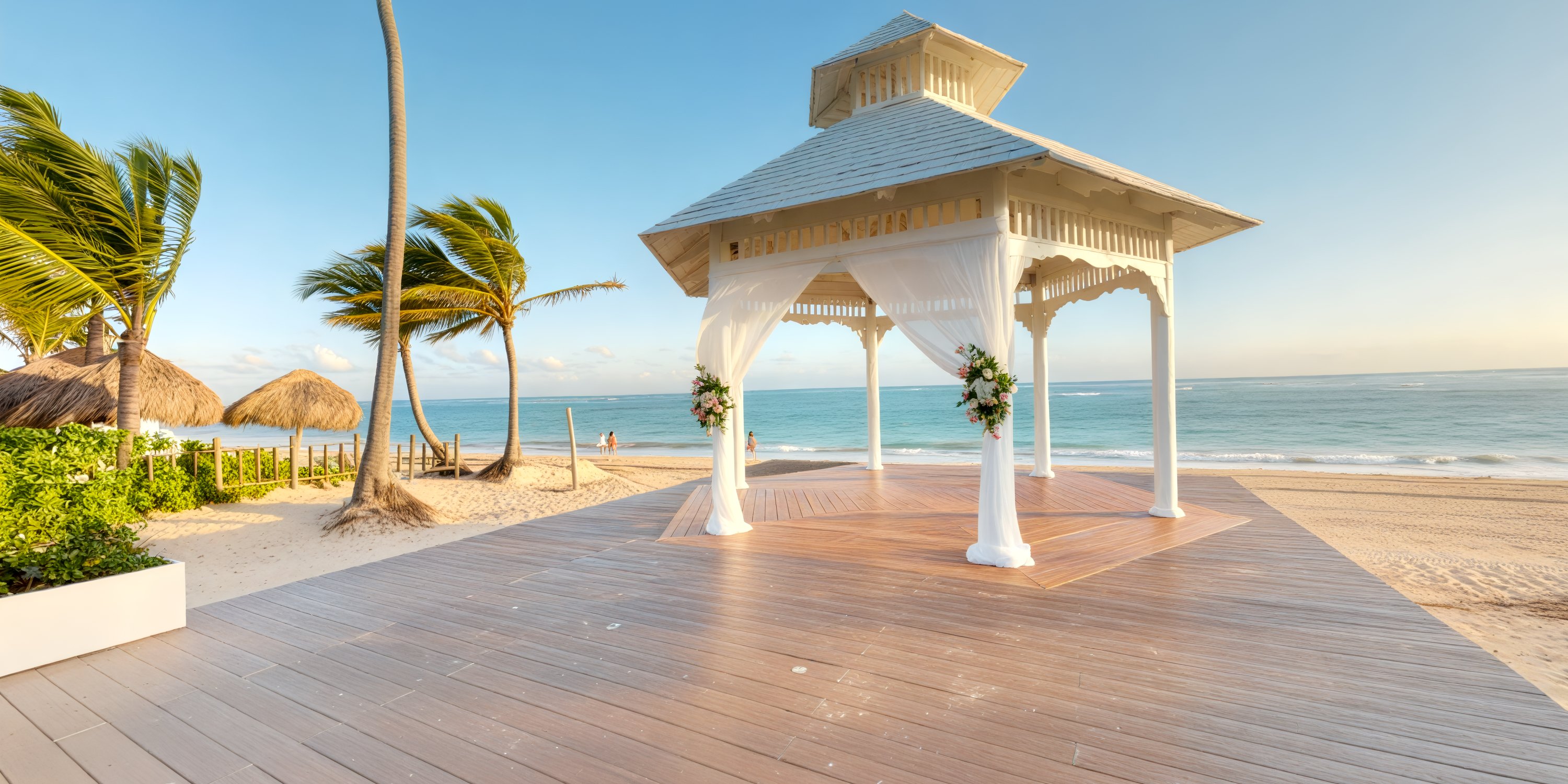 Royalton Bavaro gazebo with wedding flowers on a wooden deck overlooks the sandy beach and ocean.