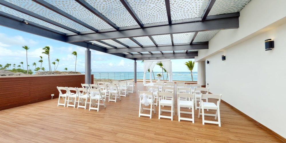 Destination wedding setup at Royalton Bavaro featuring white chairs, floral arch, and stunning ocean view.