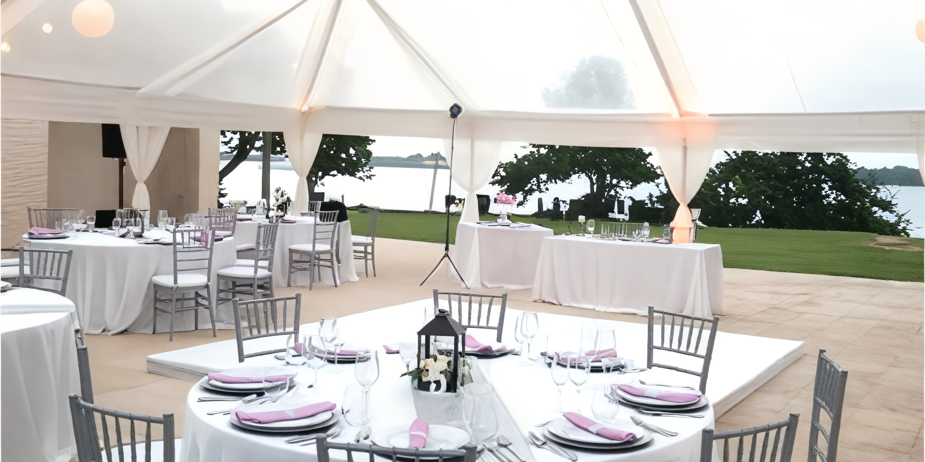 Outdoor tented destination wedding with round tables, white linens, and views of Royalton Negril.