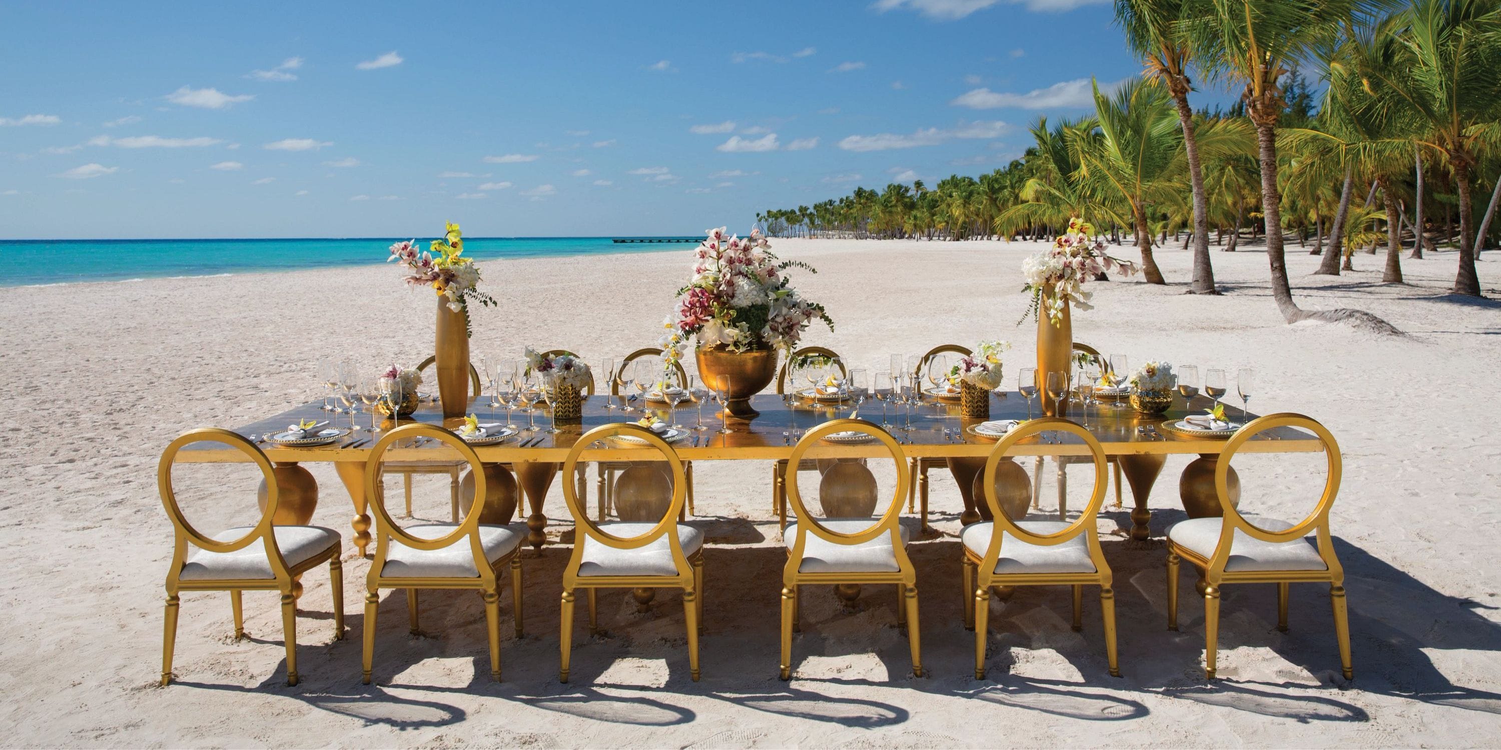 Gold chairs surround a chic dining table set for a destination wedding at Elegant Secrets Cap Cana.