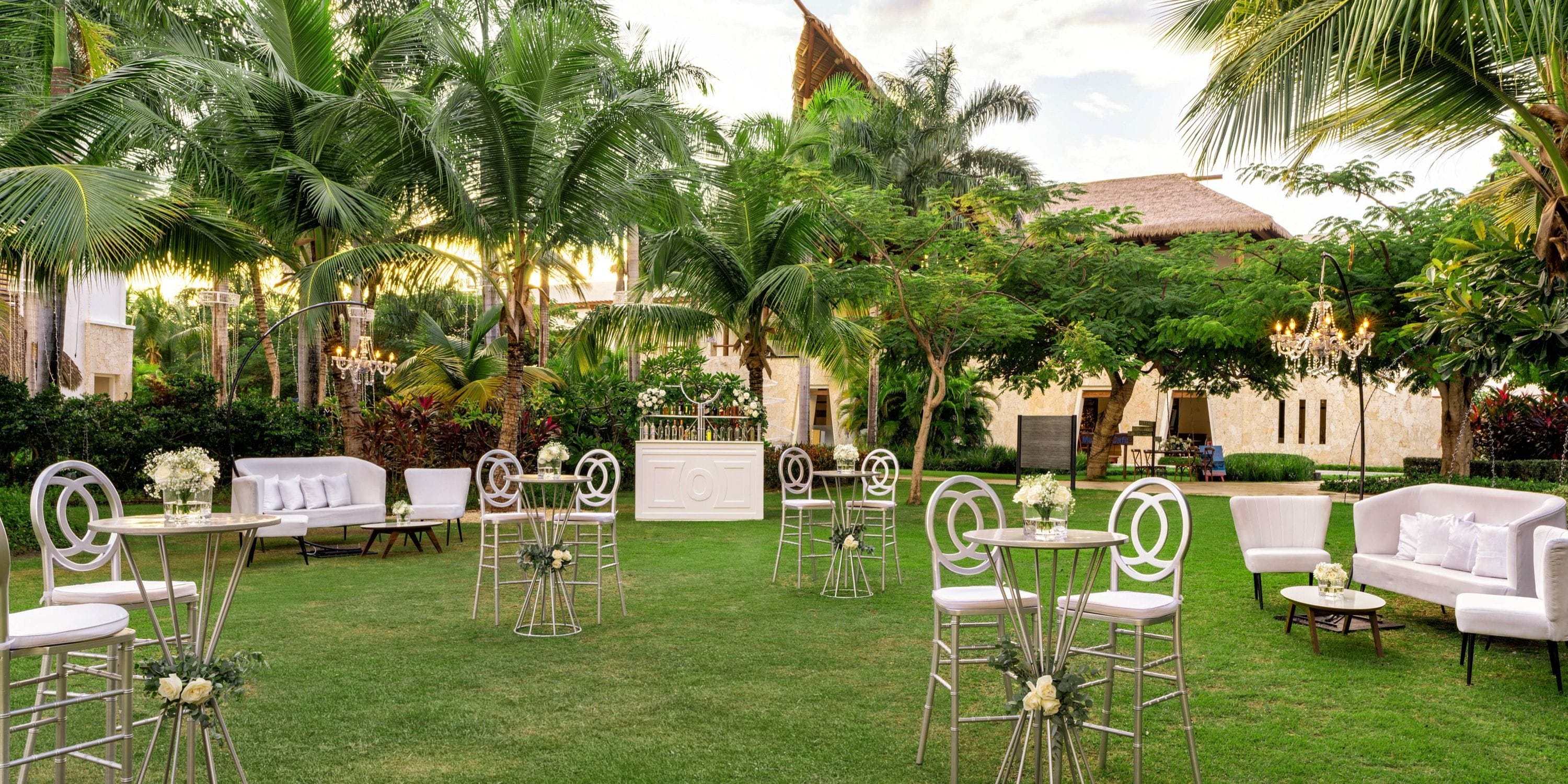 Destination wedding setup at Secrets Cap Cana featuring tables, chairs, and sofas arranged on the lawn.