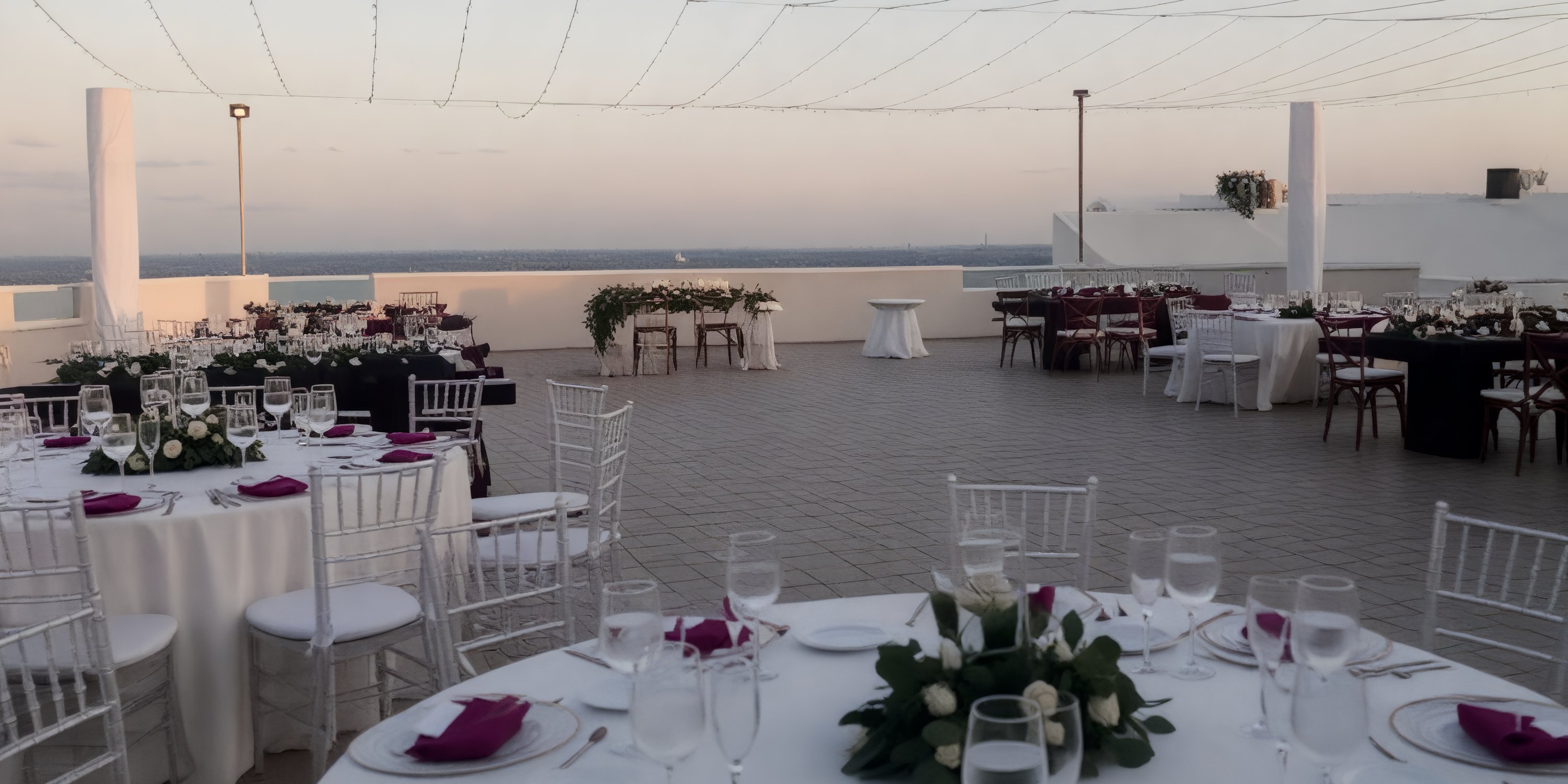 Destination wedding setup on Sunscape Cancun Resort & Spa rooftop with round tables, flowers, and napkins.