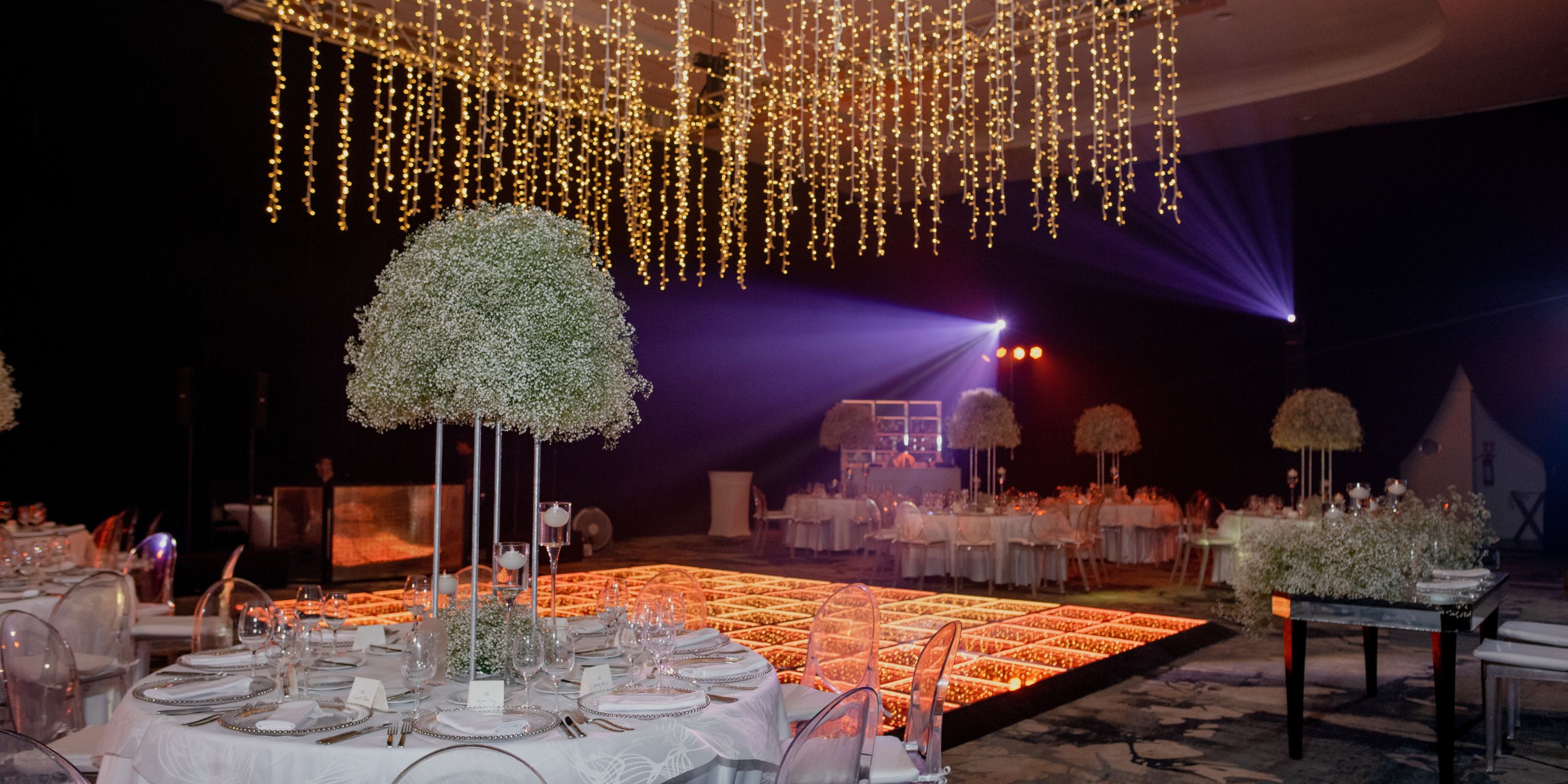 Banquet hall set for a destination wedding at UNICO 20&deg;87&deg;, featuring round tables and string lights.