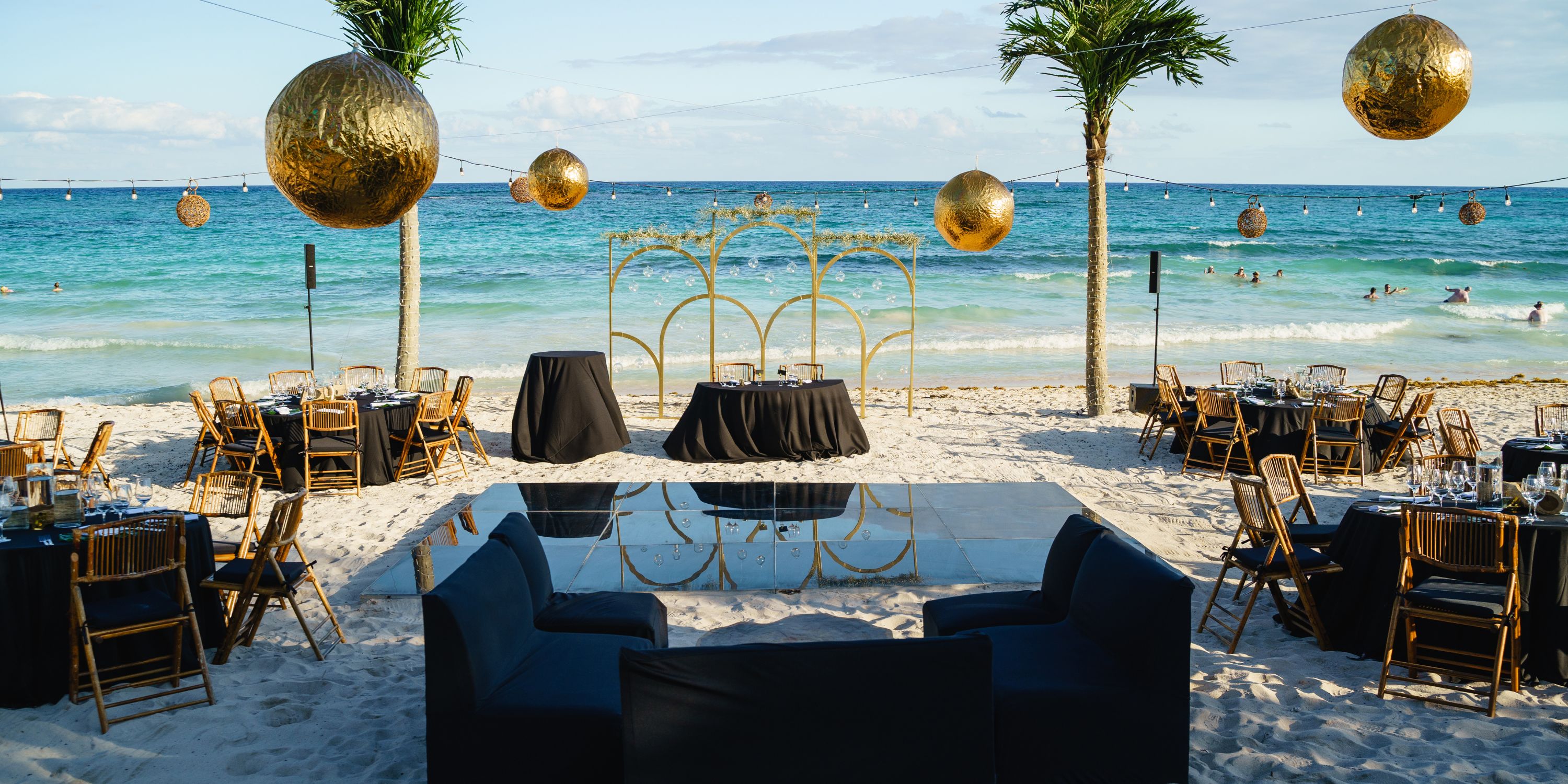 UNICO 20&deg;87&deg; Riviera Maya destination wedding setup with black & gold decor, tables, and chairs.