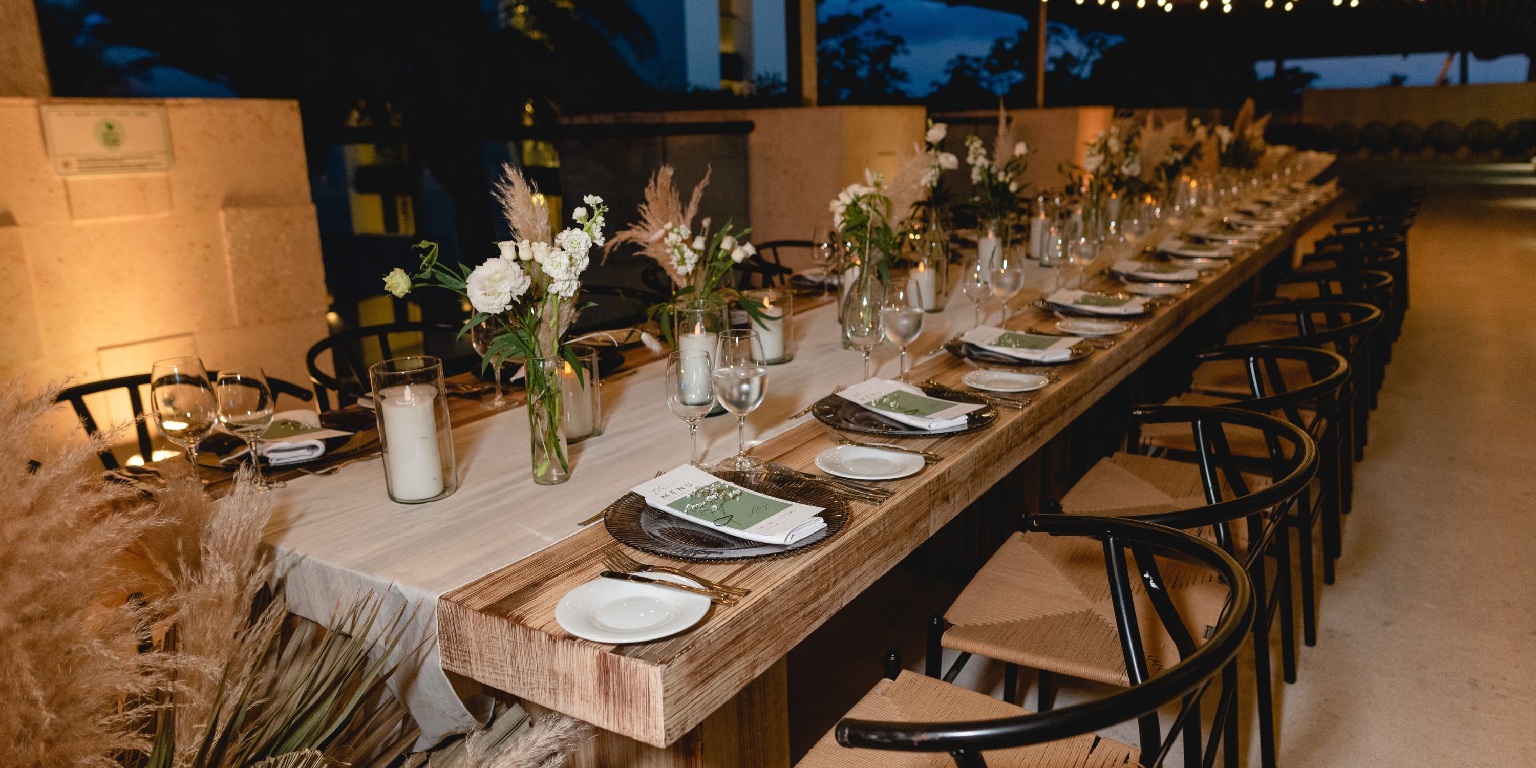 UNICO 20&deg;87&deg; Riviera Maya destination wedding table set with plates, glasses, napkins, and flowers at dusk.