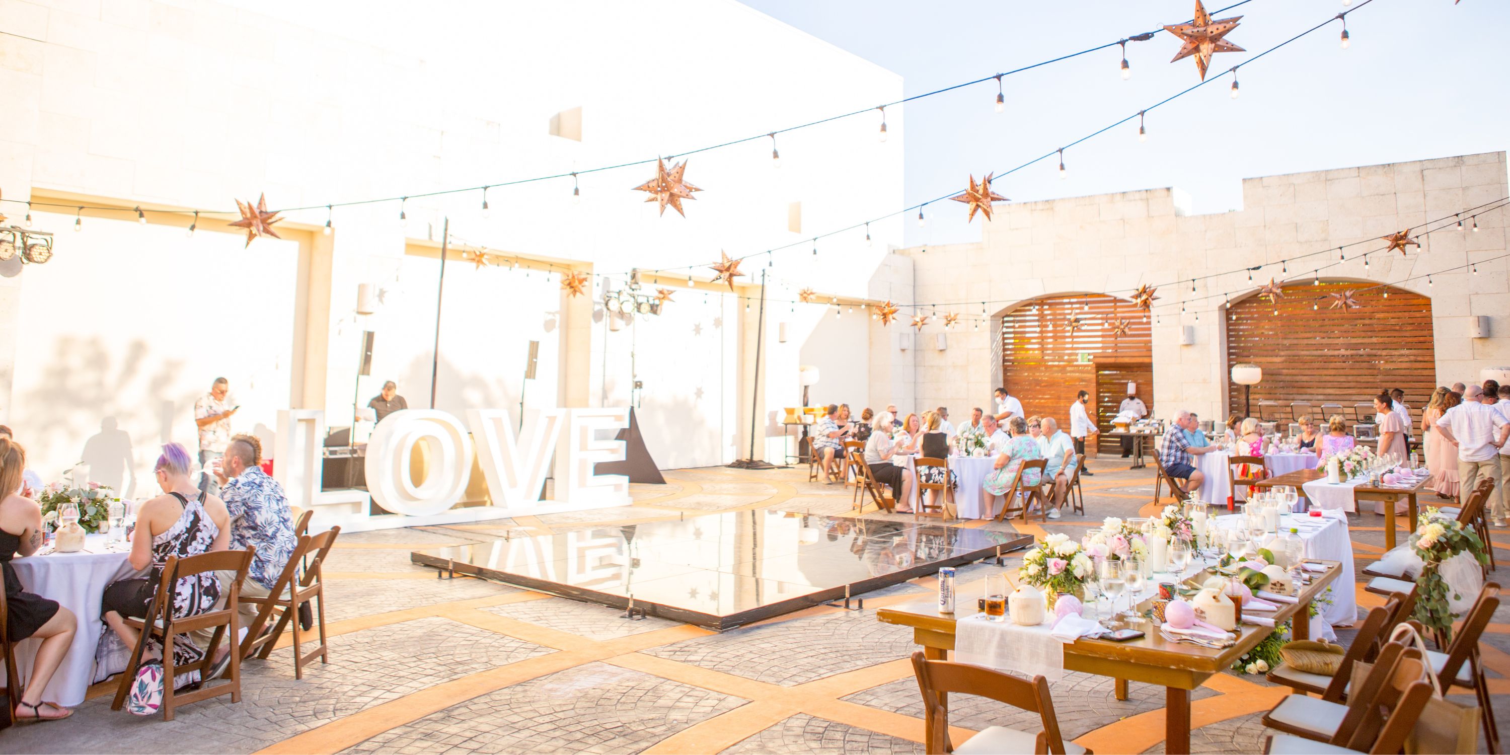 Destination wedding at UNICO 20&deg;87&deg; Riviera Maya with "LOVE" letters, festive tables, and guests.