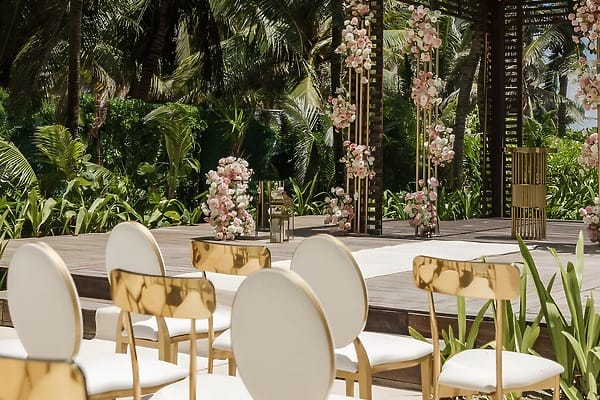 Destination wedding setup at UNICO 20&deg;87&deg; Riviera Maya, white chairs and floral decor by palm trees.