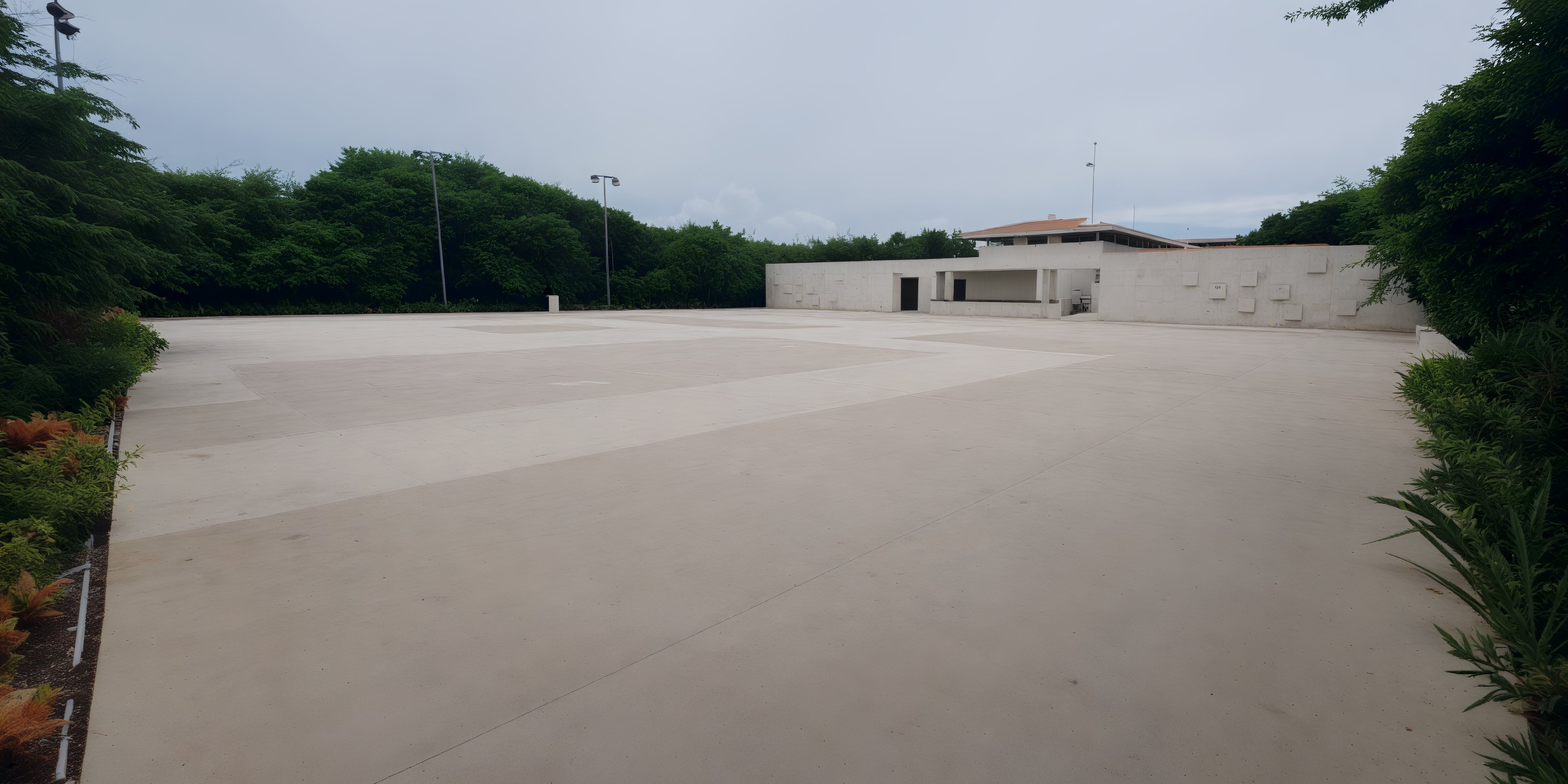 Concrete courtyard at UNICO 20°87°, ideal for a destination wedding, edged by hedges and a white building.
