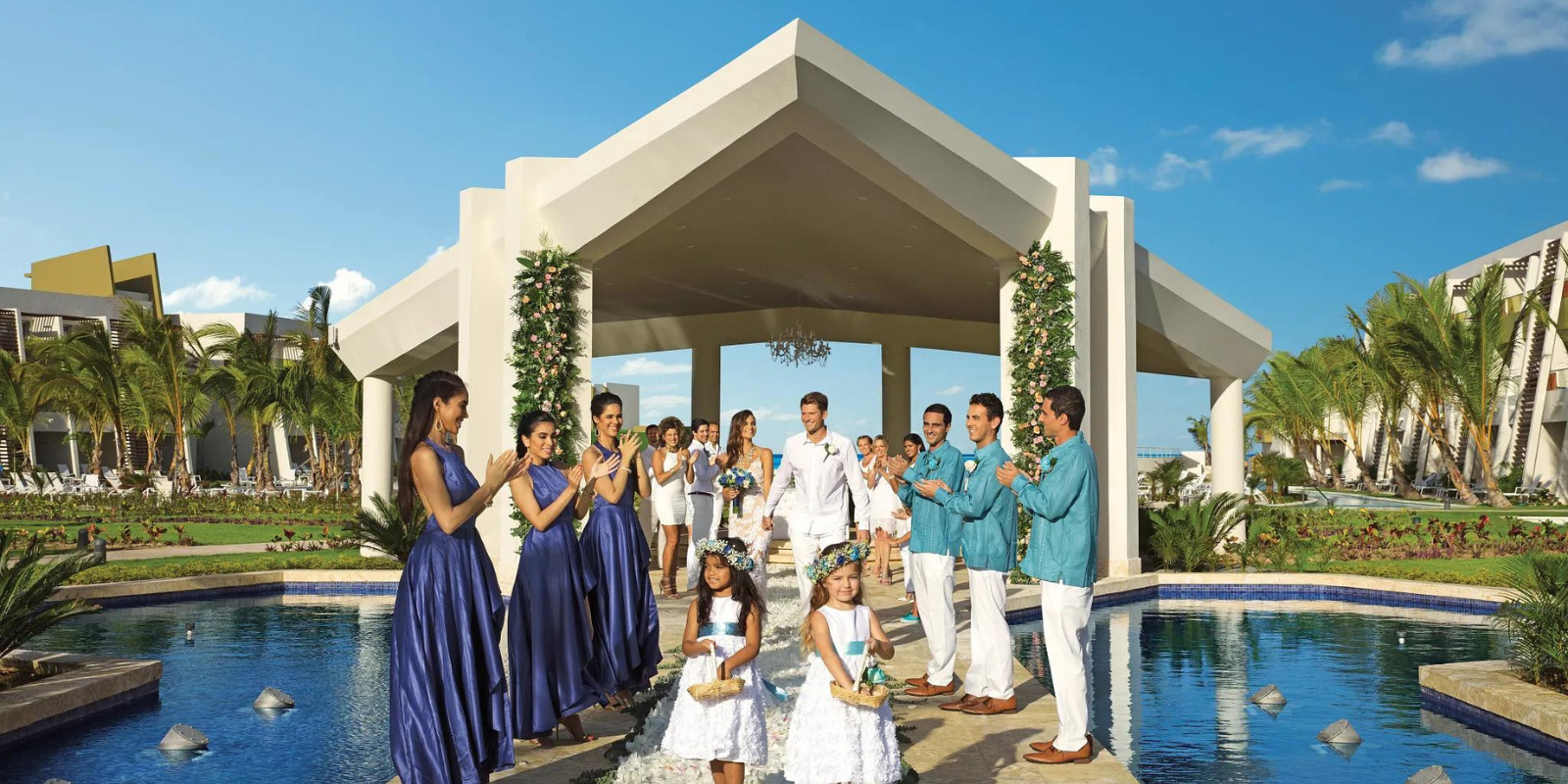 Just married couple walks down the aisle together with flower girls at the pool gazebo at Dreams Onyx Punta Cana Dominican Republic