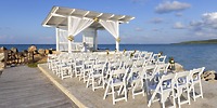 Royalton Blue Waters: destination wedding setup with white chairs facing a gazebo by the sea.