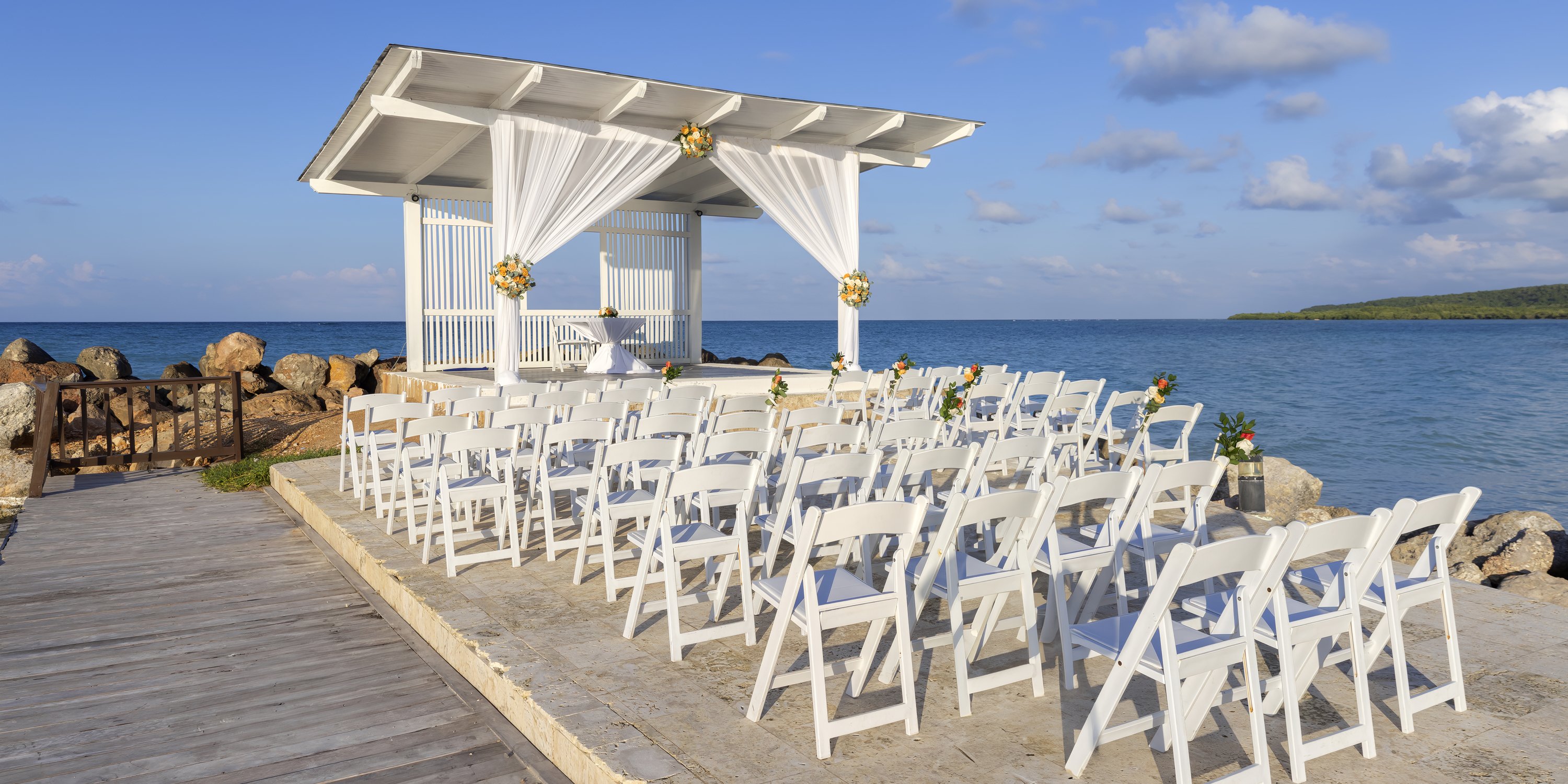 Royalton Blue Waters: destination wedding setup with white chairs facing a gazebo by the sea.