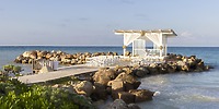 Destination wedding setup at Royalton Blue Waters on a rocky pier by the ocean under a clear sky.