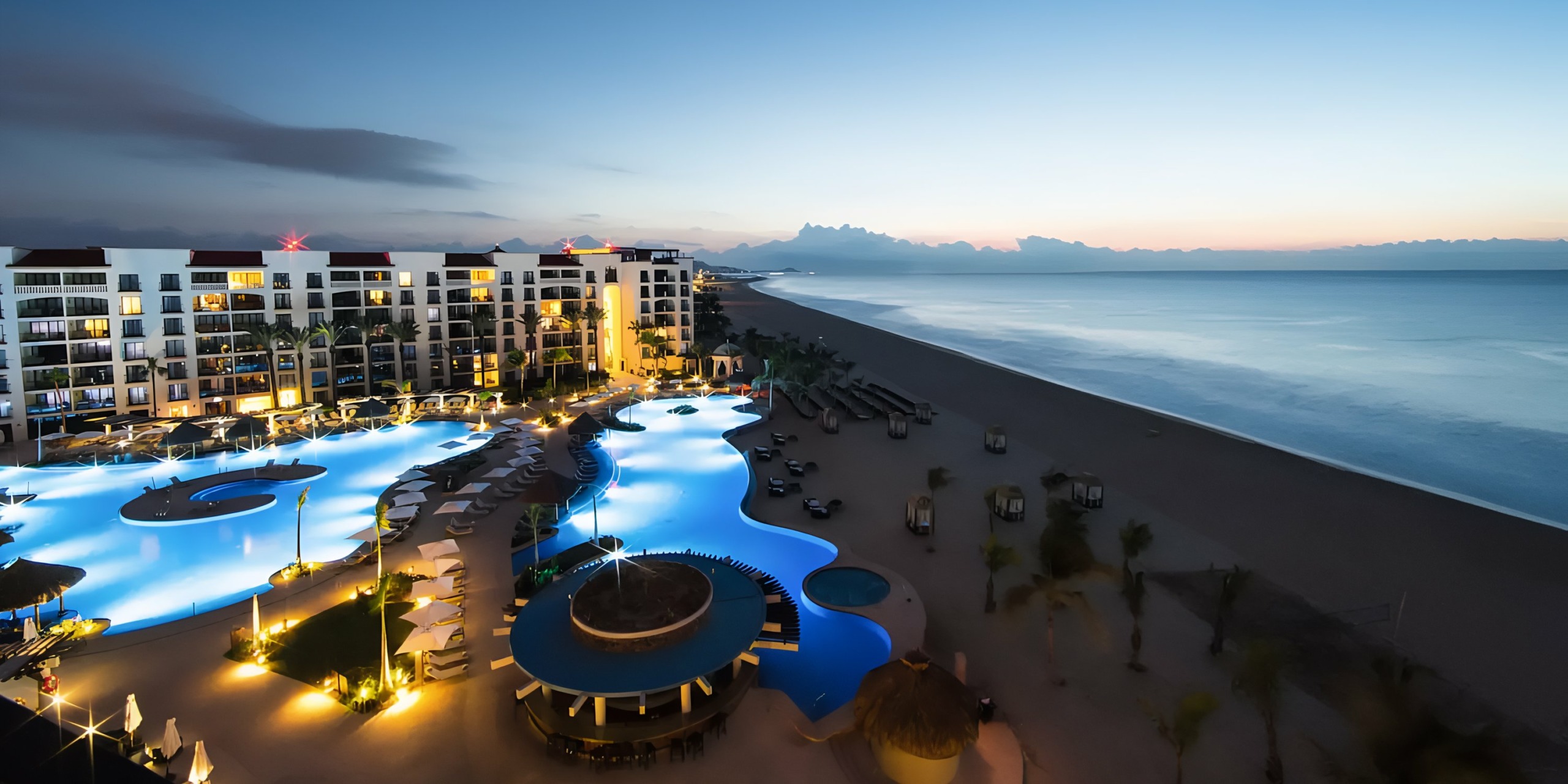 Hyatt Ziva Los Cabos with illuminated pools at twilight.