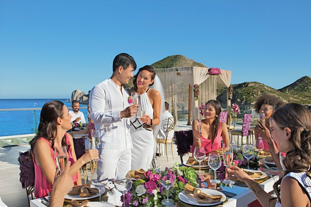 Beautiful newlyweds celebrate their destination wedding at their reception as they toast with champagne at Breathless Cabo San Lucas