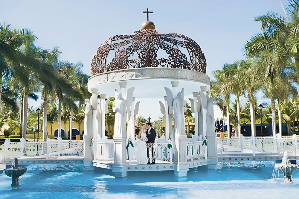 A couple getting married under a lavish and beautiful poolside gazebo at a destination wedding on a beautiful day