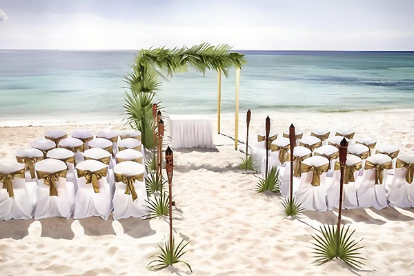 Destination wedding setup at Barcelo Bavaro Beach with white chairs, gold sashes, and ocean views.