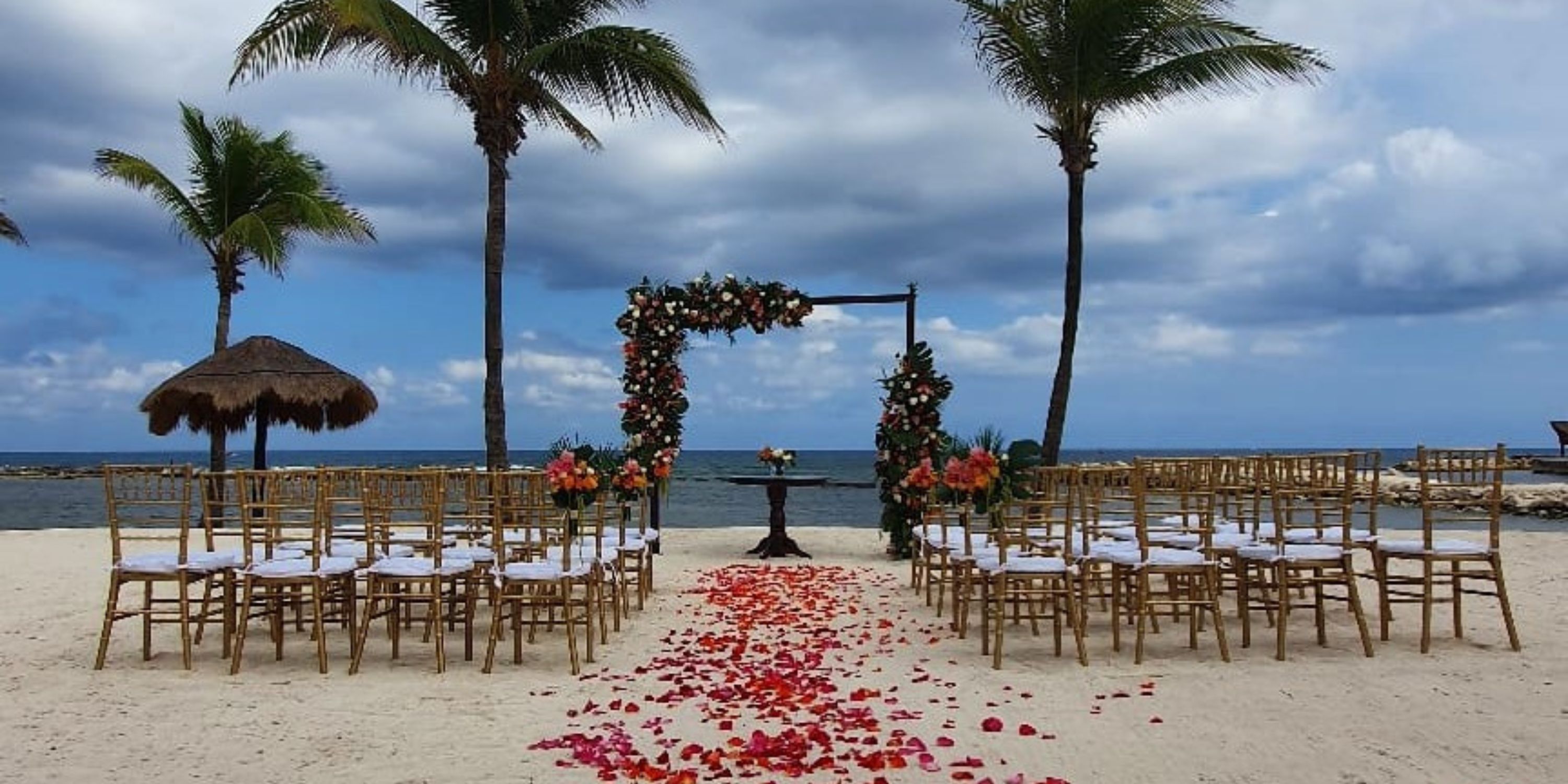 Beach destination wedding setup at Catalonia Riviera Maya with chairs and a floral arch for the ceremony.