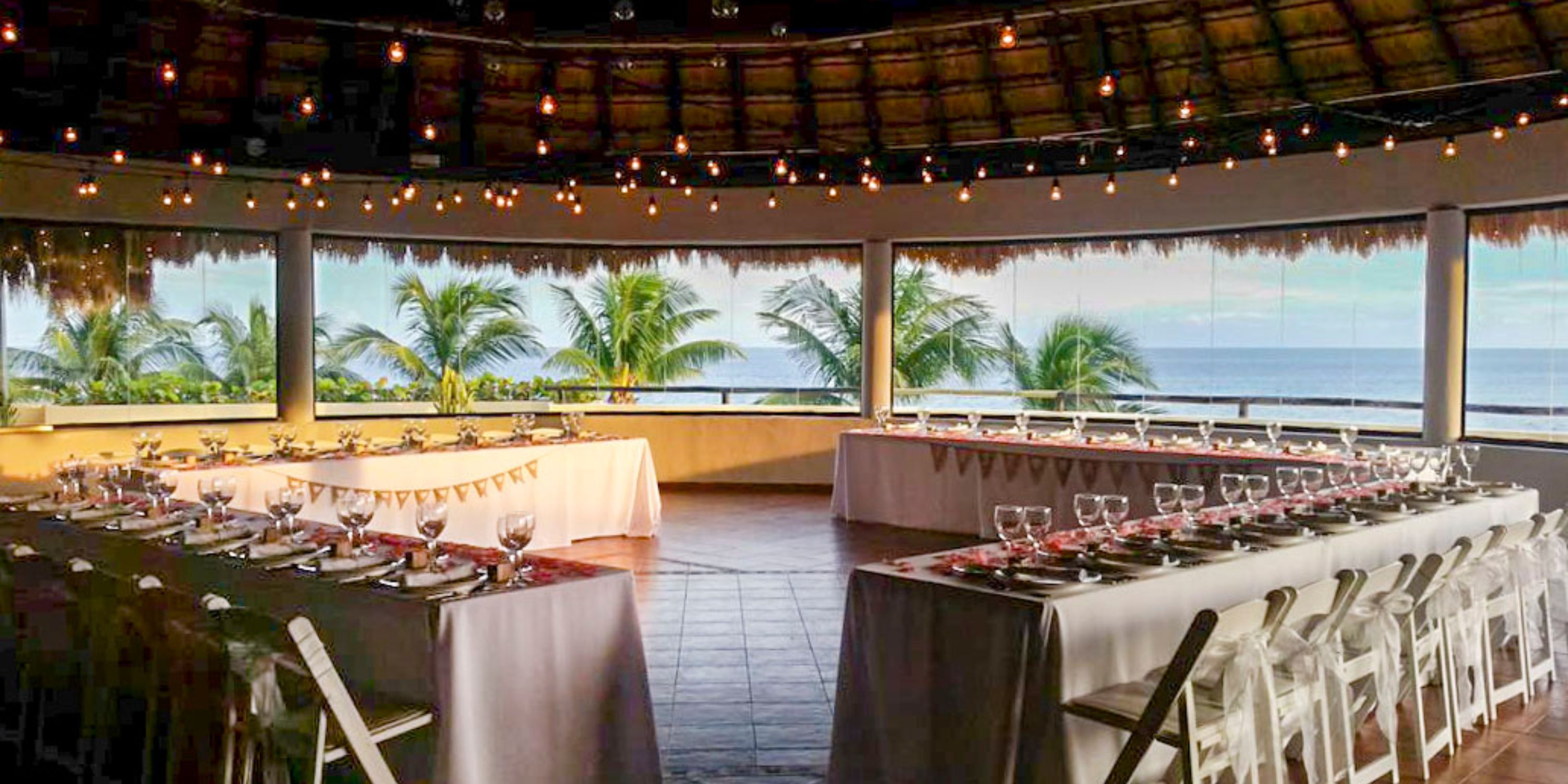 Tables arranged for a destination wedding at Catalonia Riviera Maya, ocean and palm trees behind.