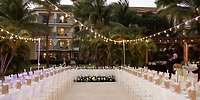 Destination wedding outdoor reception at Dreams Royal Beach Punta Cana with long tables, string lights, palms.