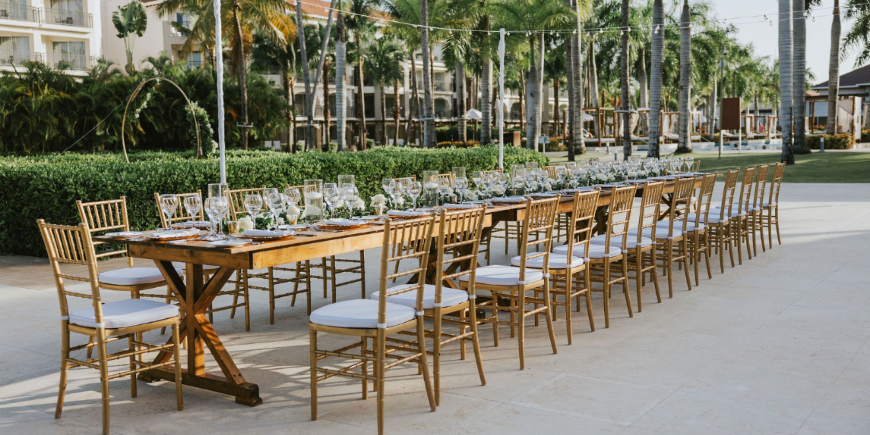 Destination wedding outdoor dining at Dreams Royal Beach Punta Cana with gold chairs, palms, and greenery.