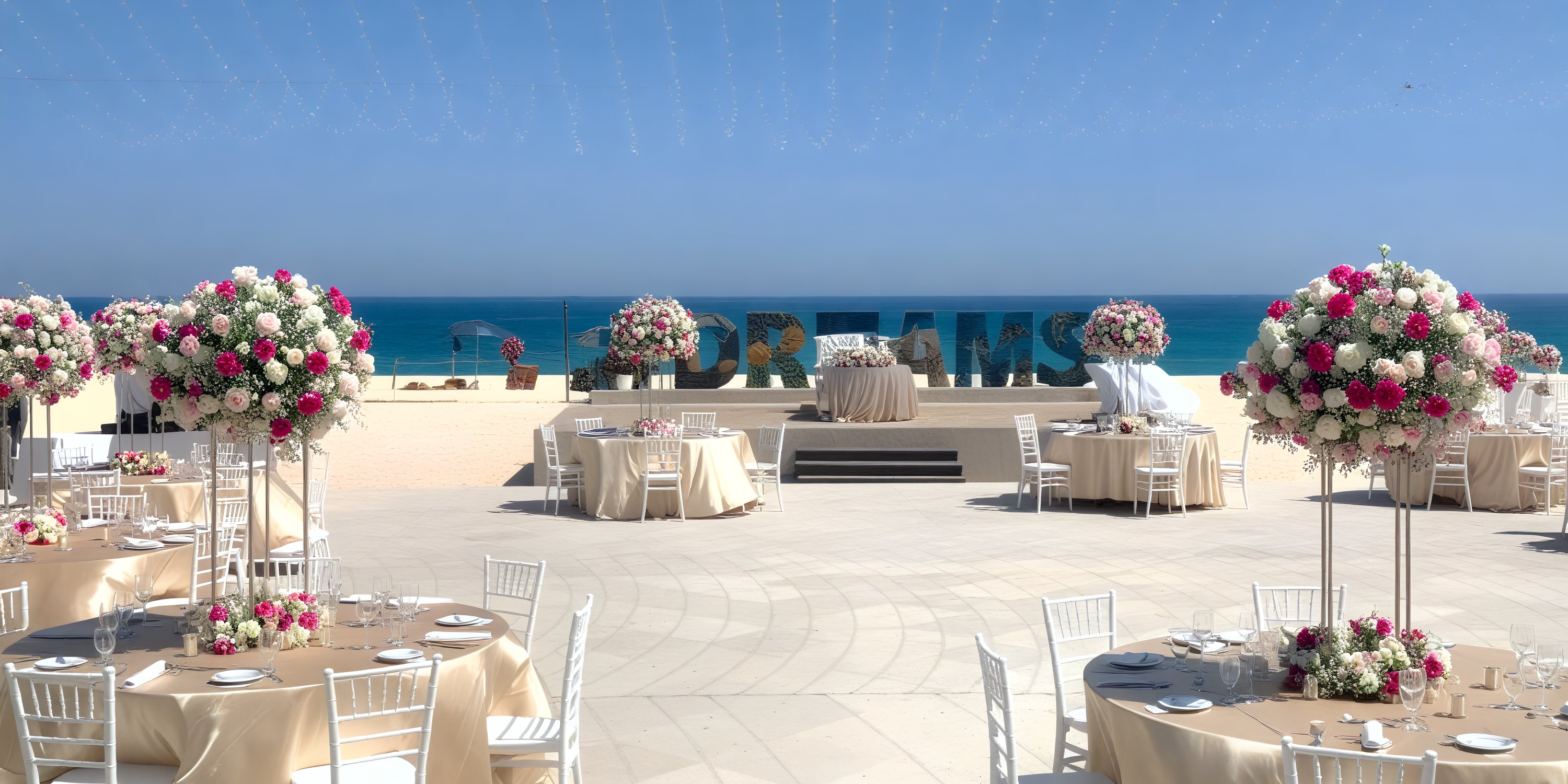 Experience the perfect destination wedding at Dreams Los Cabos, featuring round tables adorned with oceanfront floral arrangements.