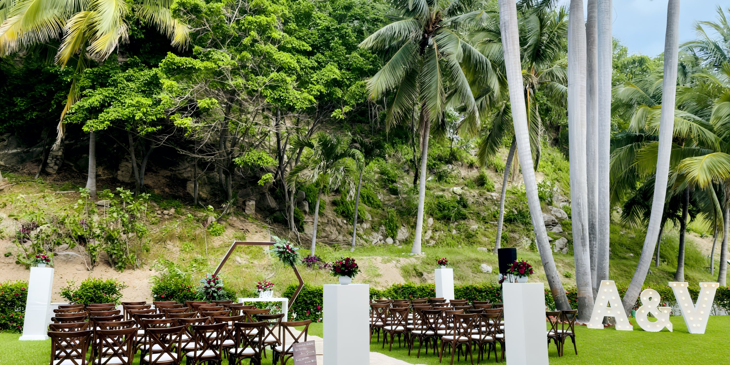 Destination wedding ceremony at Dreams Huatulco with wooden chairs, floral decor, and large A&V letters.
