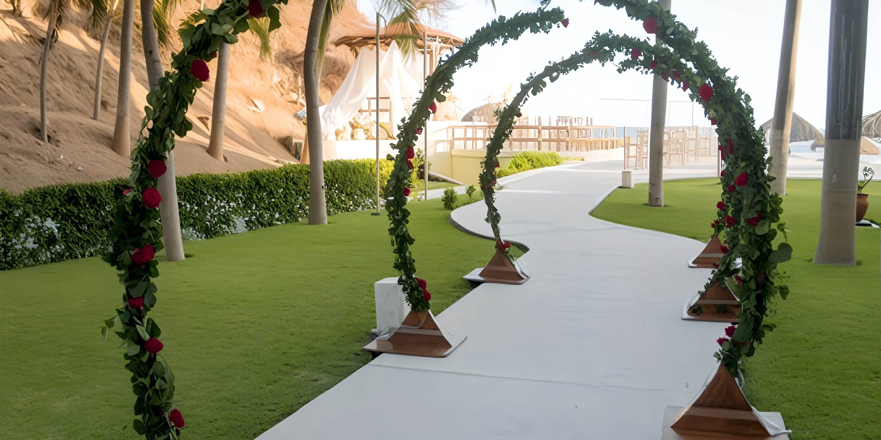 Four floral arches line the white path of a destination wedding at Dreams Huatulco's beachside lawn.