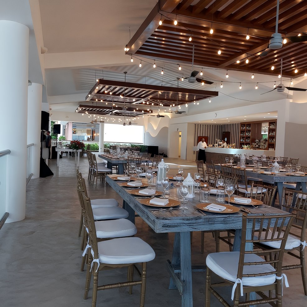 Modern restaurant interior set up for a destination wedding, with wooden chairs and ceiling string lights.