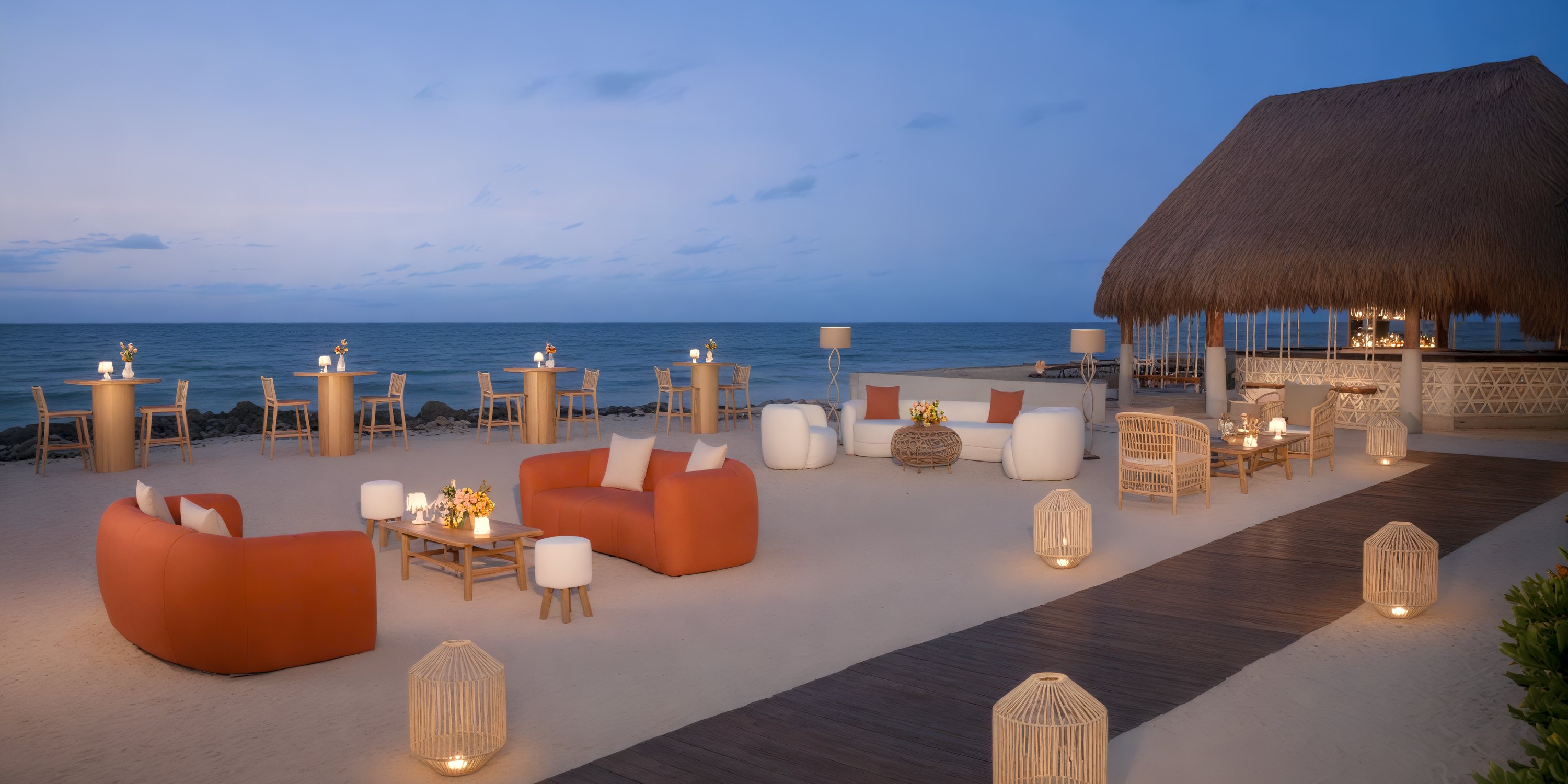 Dreams Aventuras Riviera Maya: beachside lounge with orange sofas, wood tables & lanterns—ideal for a destination wedding at sunset.